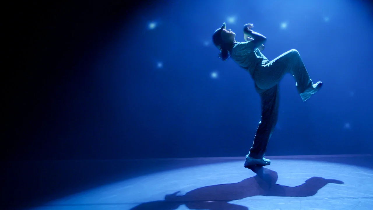 Rachael “Raygun” Gunn performs under blue stage lights in an official Netflix still from Untold Raygun: Breaking Badly.
