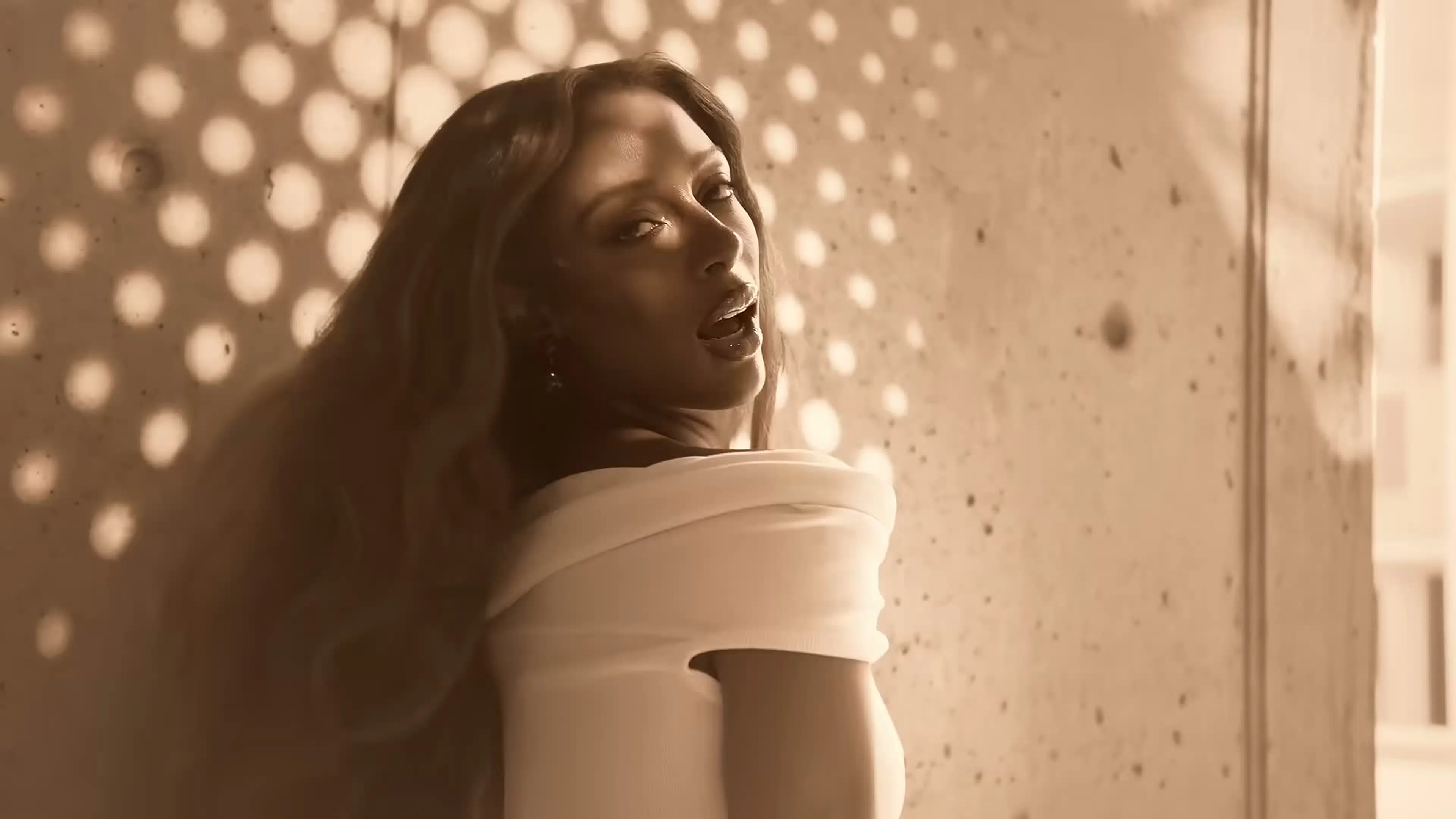 Victoria Monét turns toward the camera in a white outfit in Reach Out.