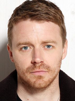 Portrait of Jack Lowden with short reddish-brown hair and a beard.