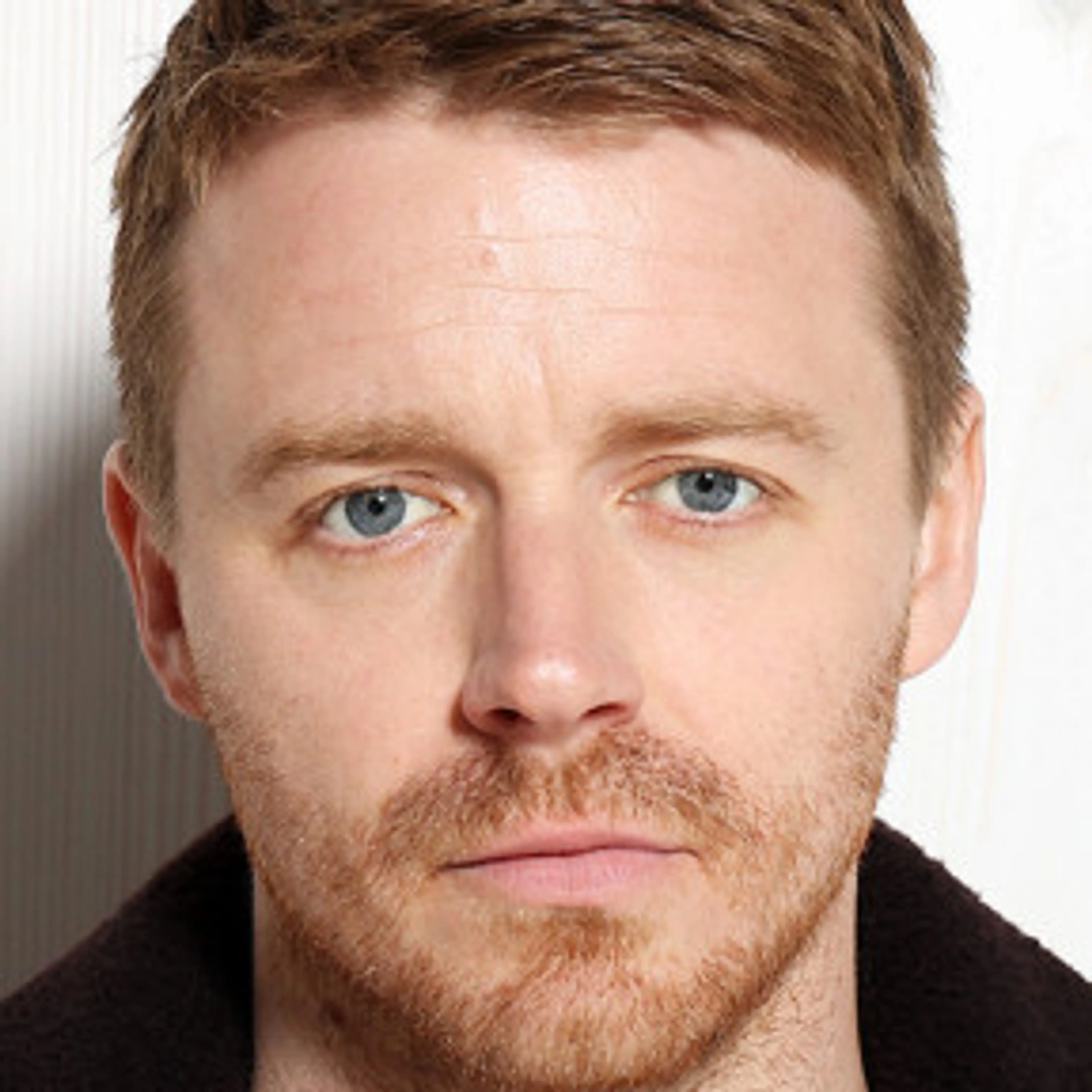 Portrait of Jack Lowden with short reddish-brown hair and a beard.