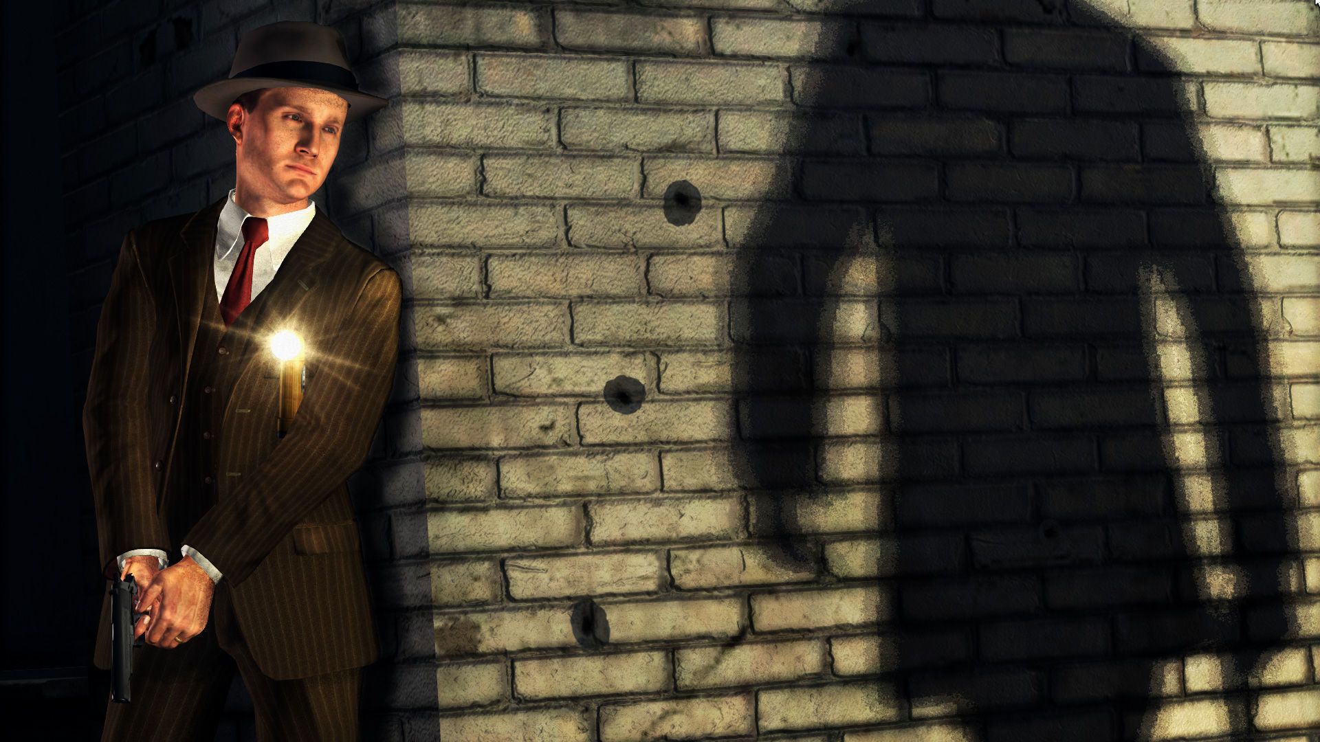 A suited detective holds a handgun behind a wall marked by bullet holes.
