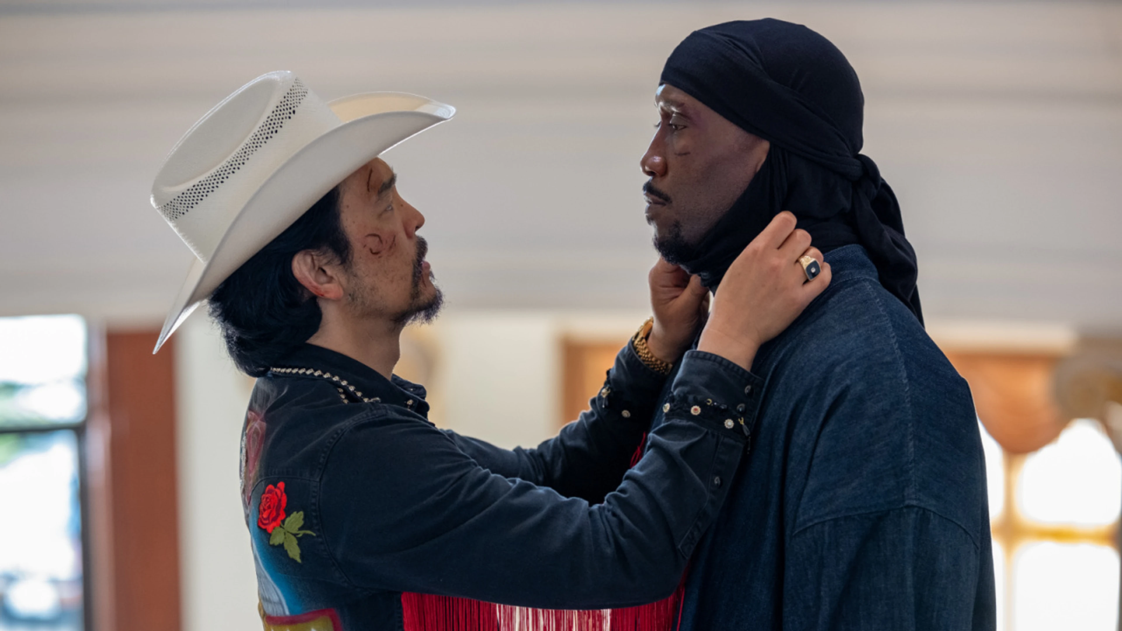 John Cho in a white cowboy hat faces Mahershala Ali on the set of Your Mother Your Mother Your Mother.