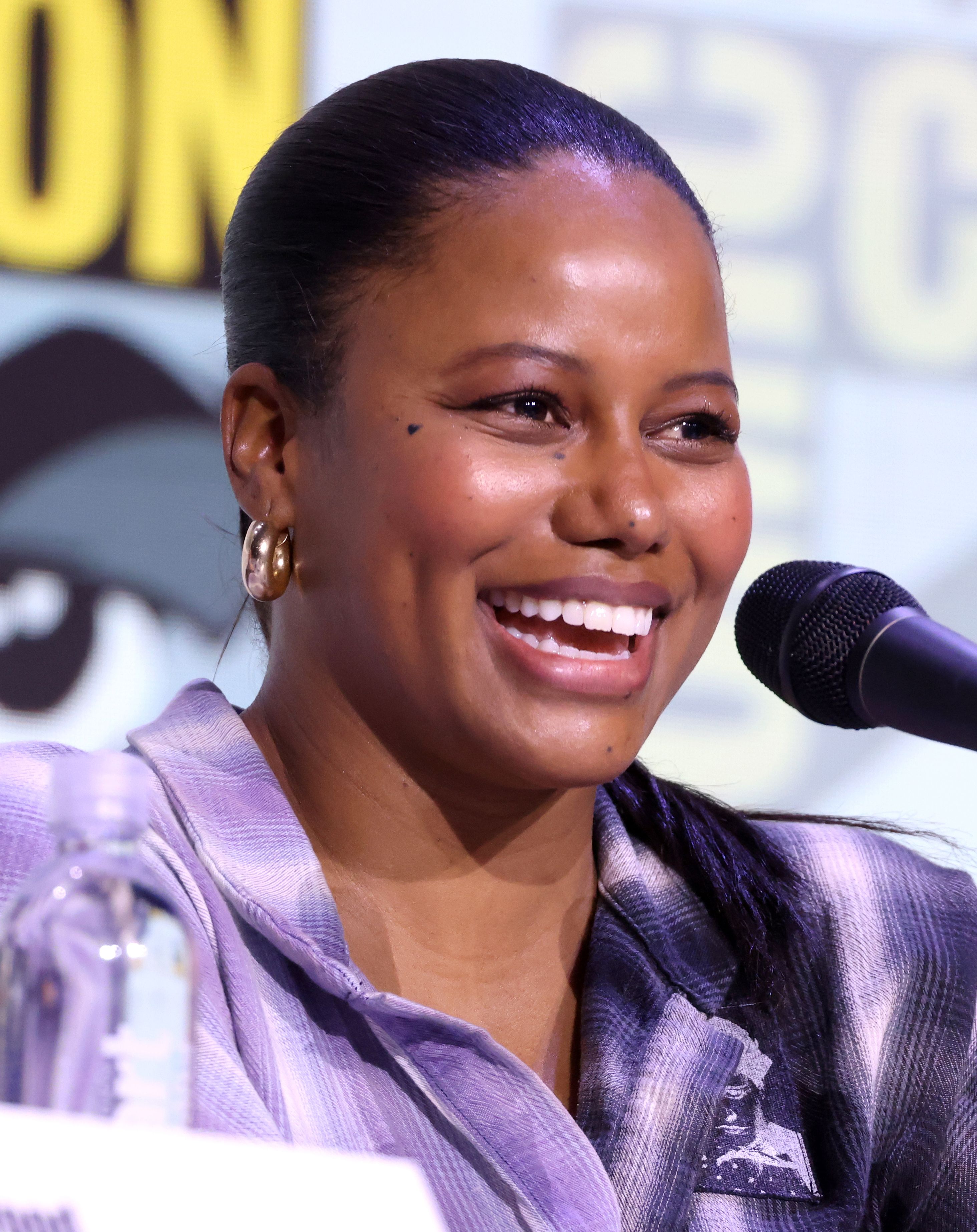 Taylour Paige speaking into a microphone at San Diego Comic-Con in 2025.