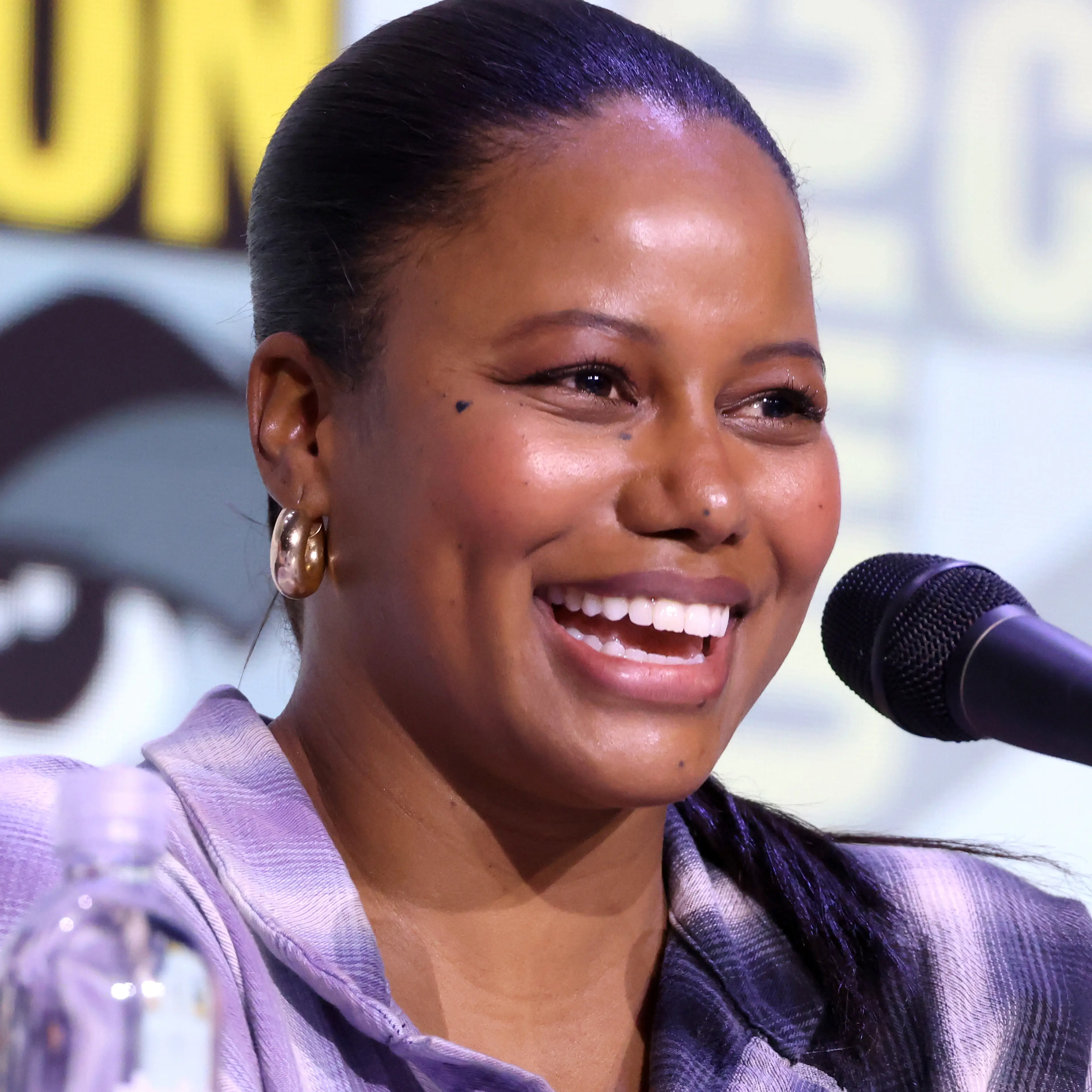 Taylour Paige speaking into a microphone at San Diego Comic-Con in 2025.
