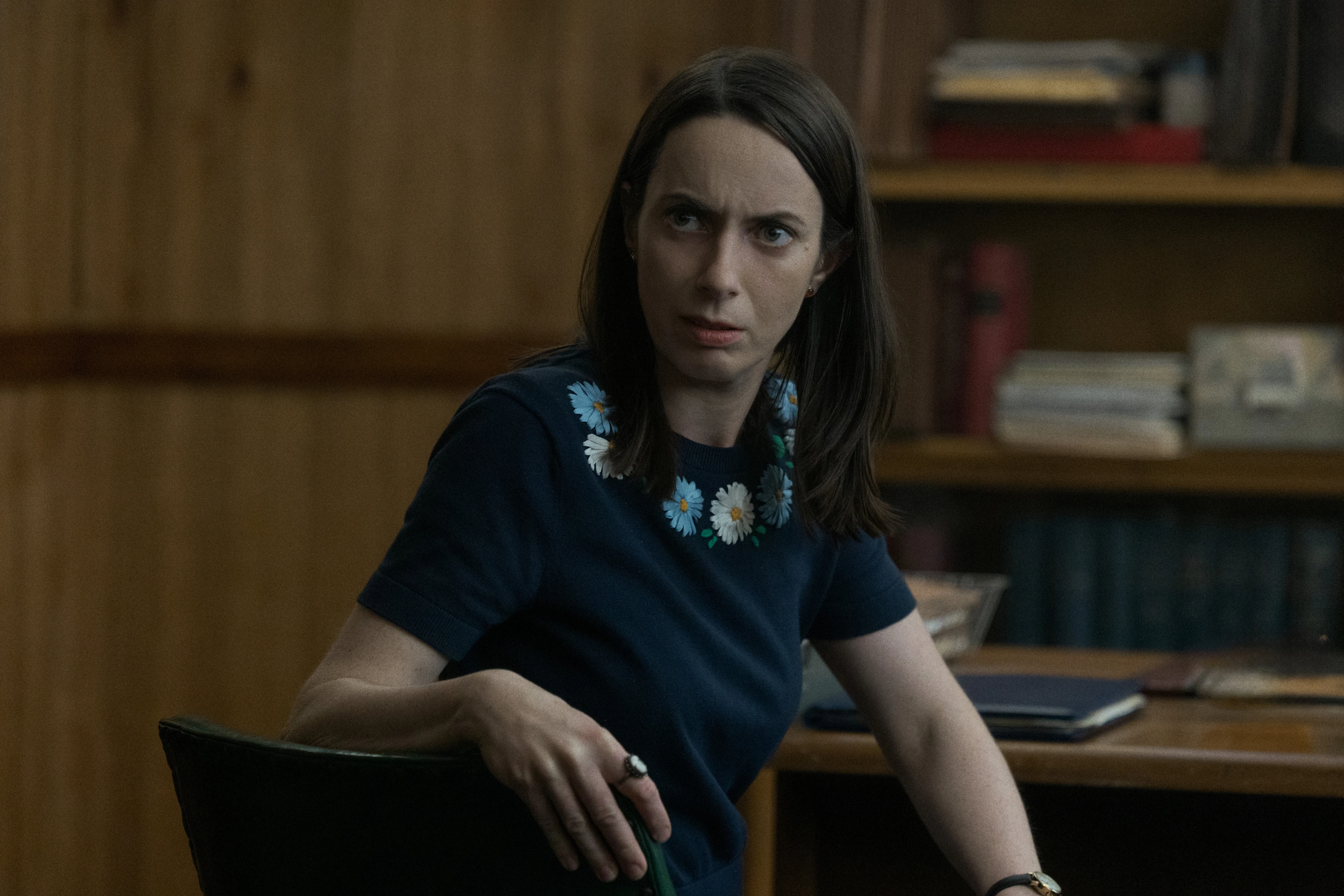 Kate O’Flynn as Patricia sits in a patterned chair in Widow’s Bay.