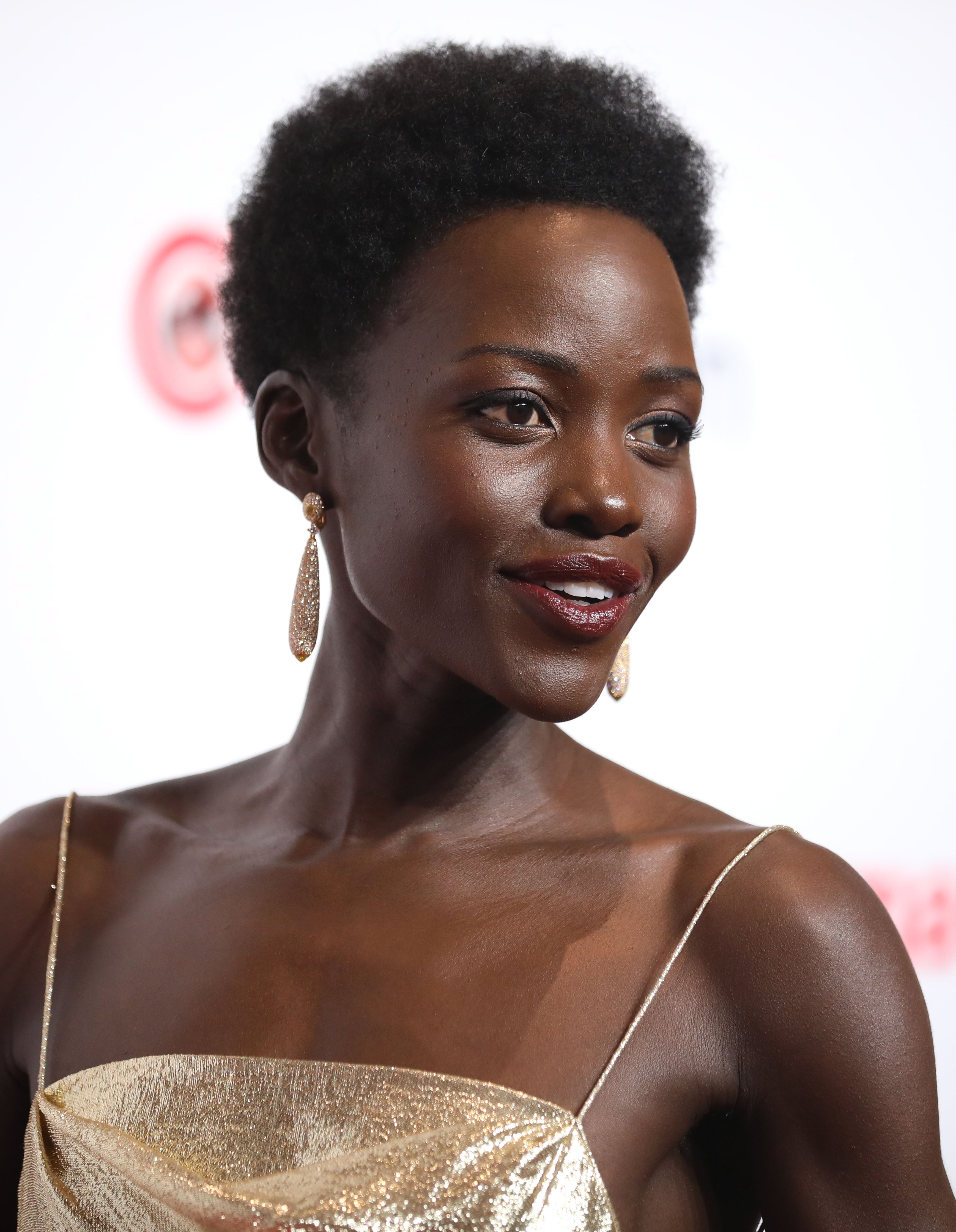 Lupita Nyong’o wearing a gold dress and earrings at CinemaCon in April 2024.