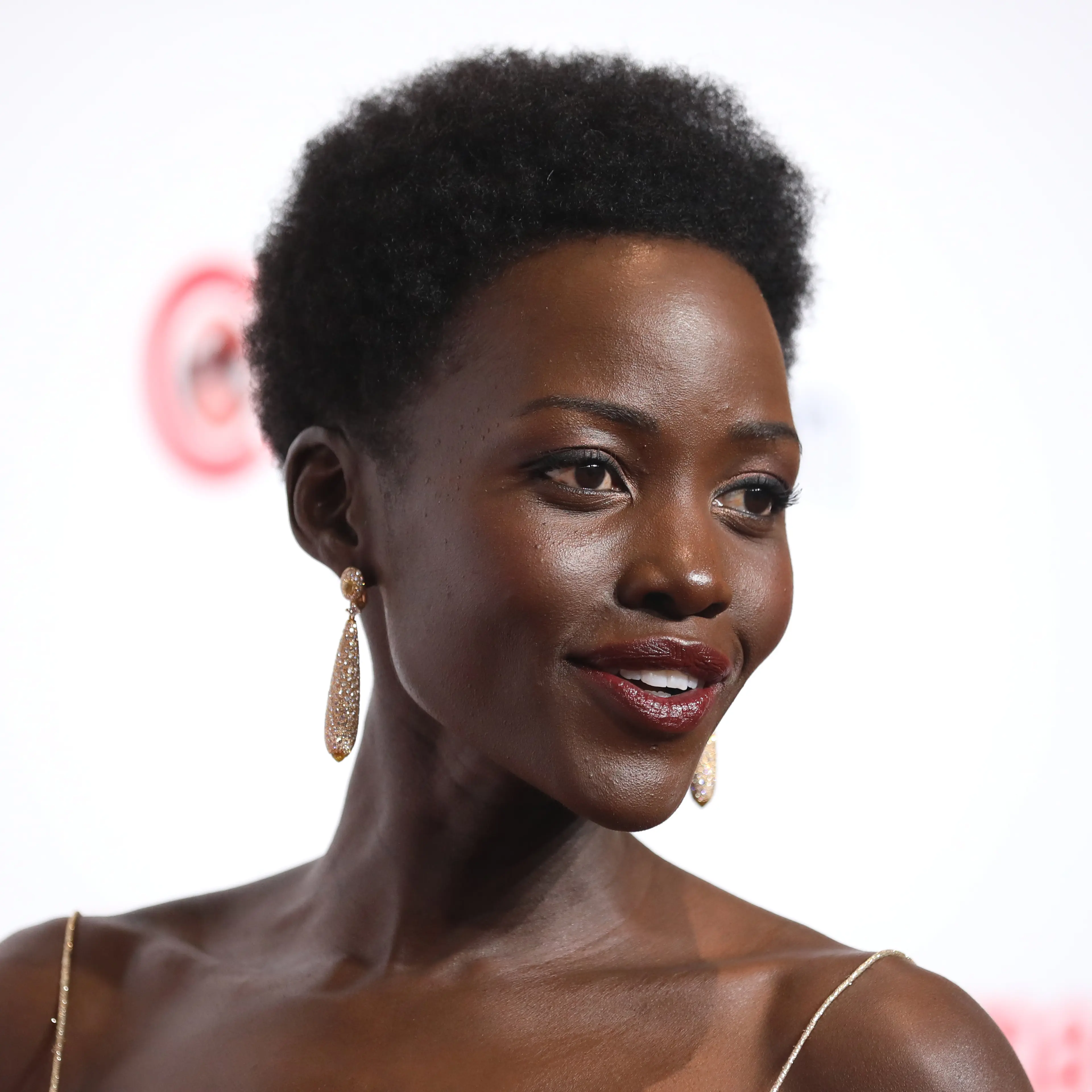 Lupita Nyong’o wearing a gold dress and earrings at CinemaCon in April 2024.