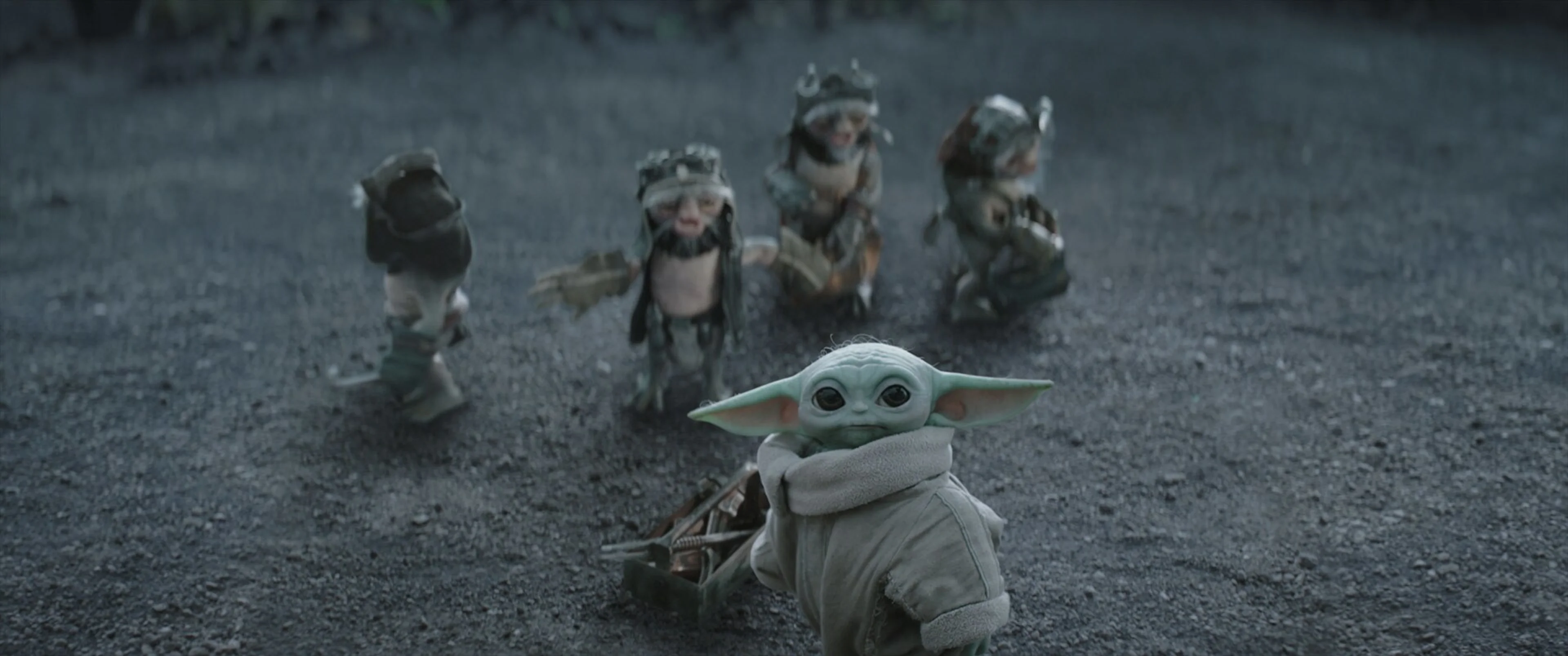 Grogu looks up with four small Anzellan mechanics behind him.
