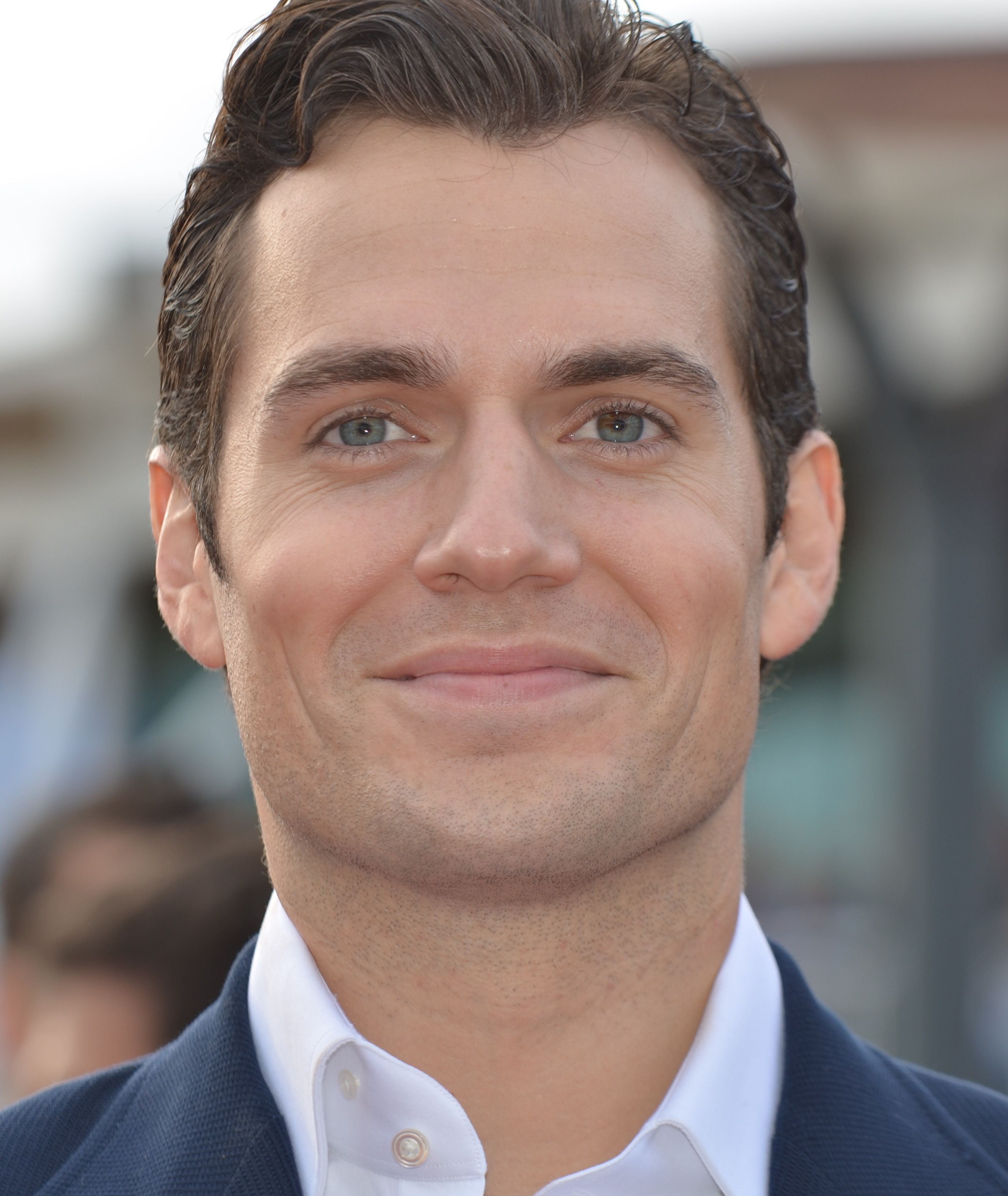Henry Cavill smiles in a dark suit and white shirt in 2013.