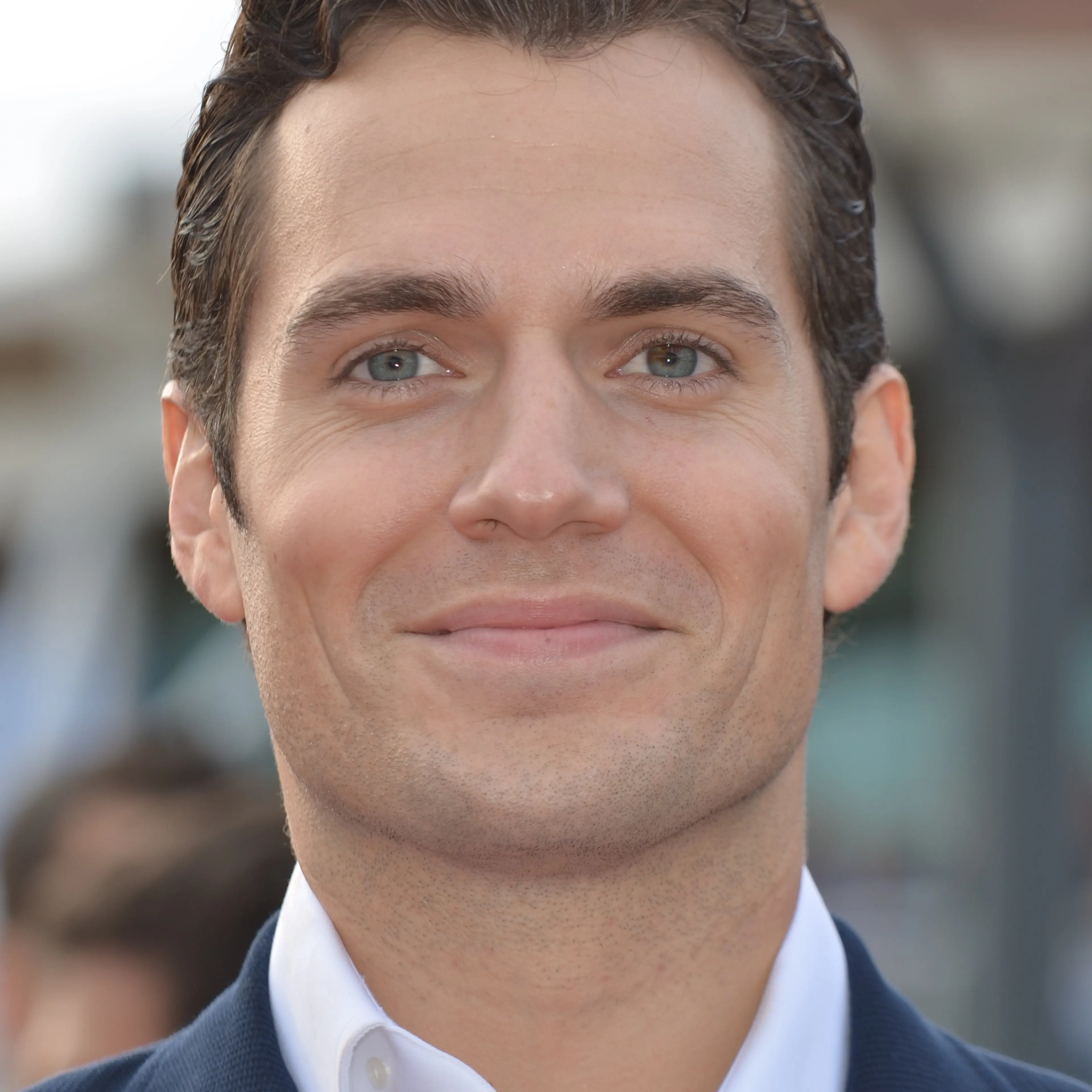 Henry Cavill smiles in a dark suit and white shirt in 2013.