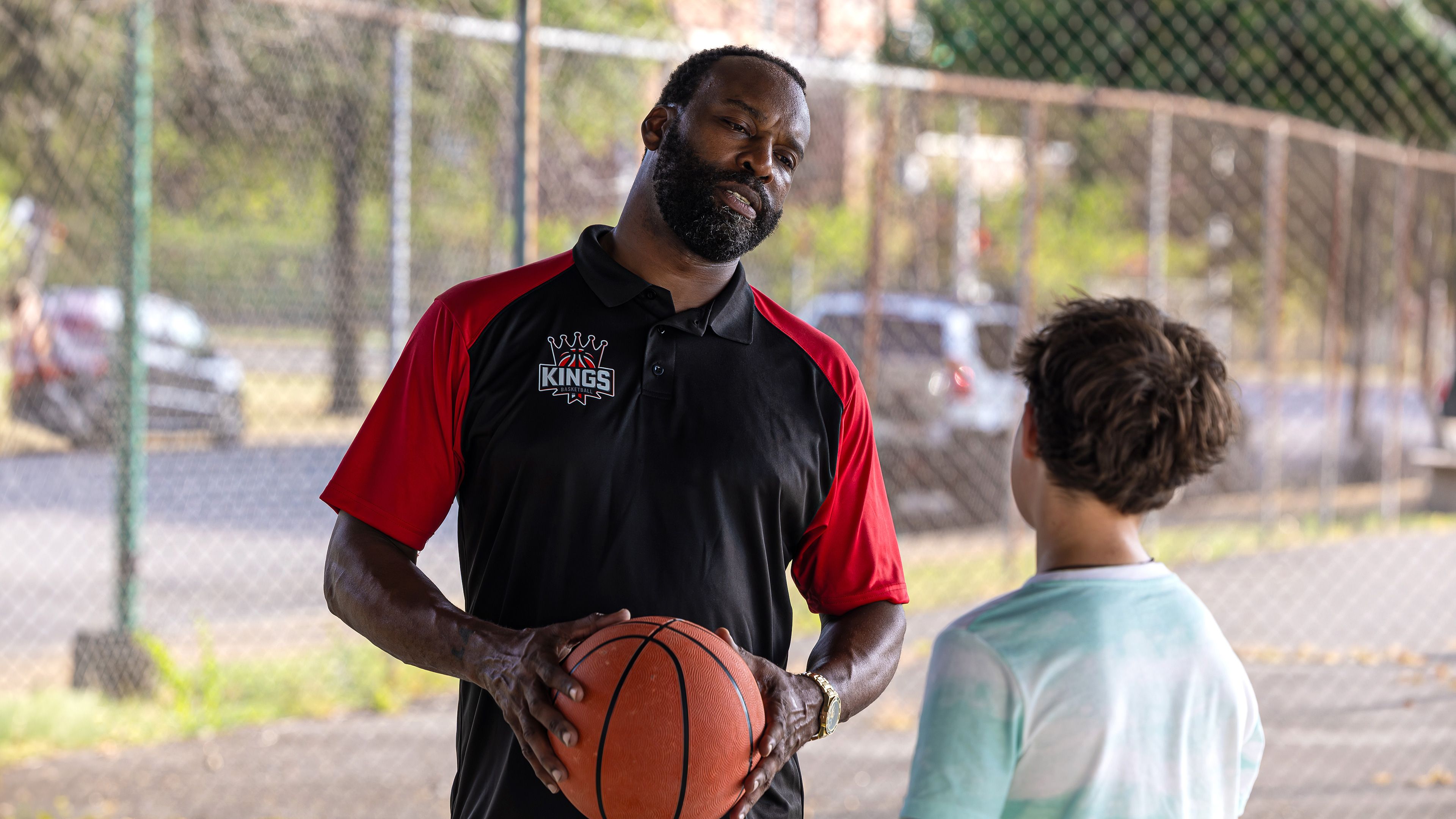 Baron Davis holds a basketball beside Dylan Friedman on an outdoor court in Last Shot.
