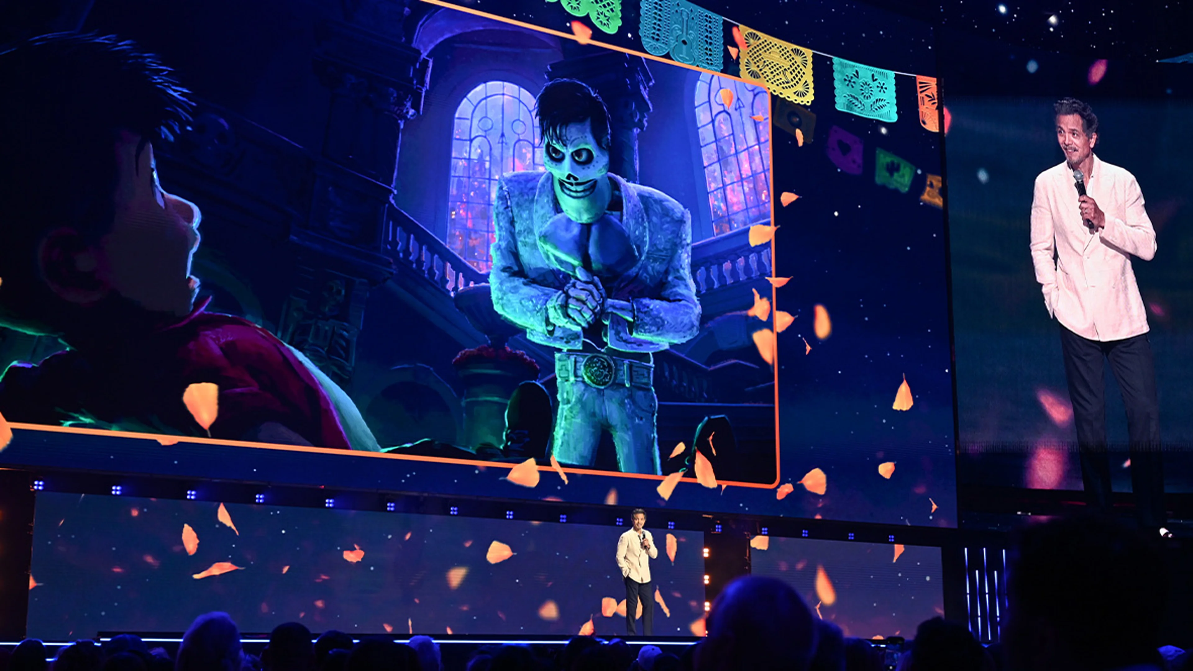 Benjamin Bratt speaks at D23 beside Coco 2 artwork featuring Ernesto de la Cruz.