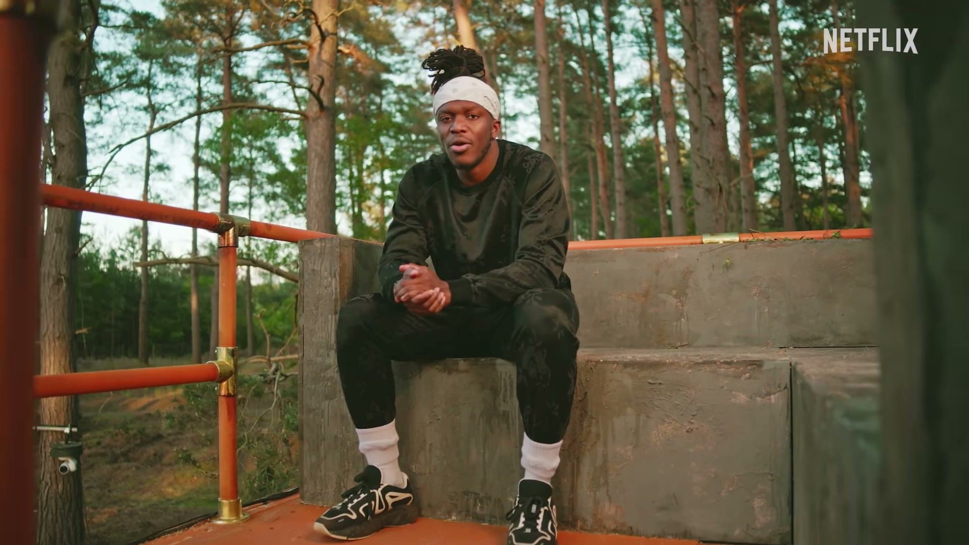 A Sidemen member sits on steps in the woods in the official Outside trailer.