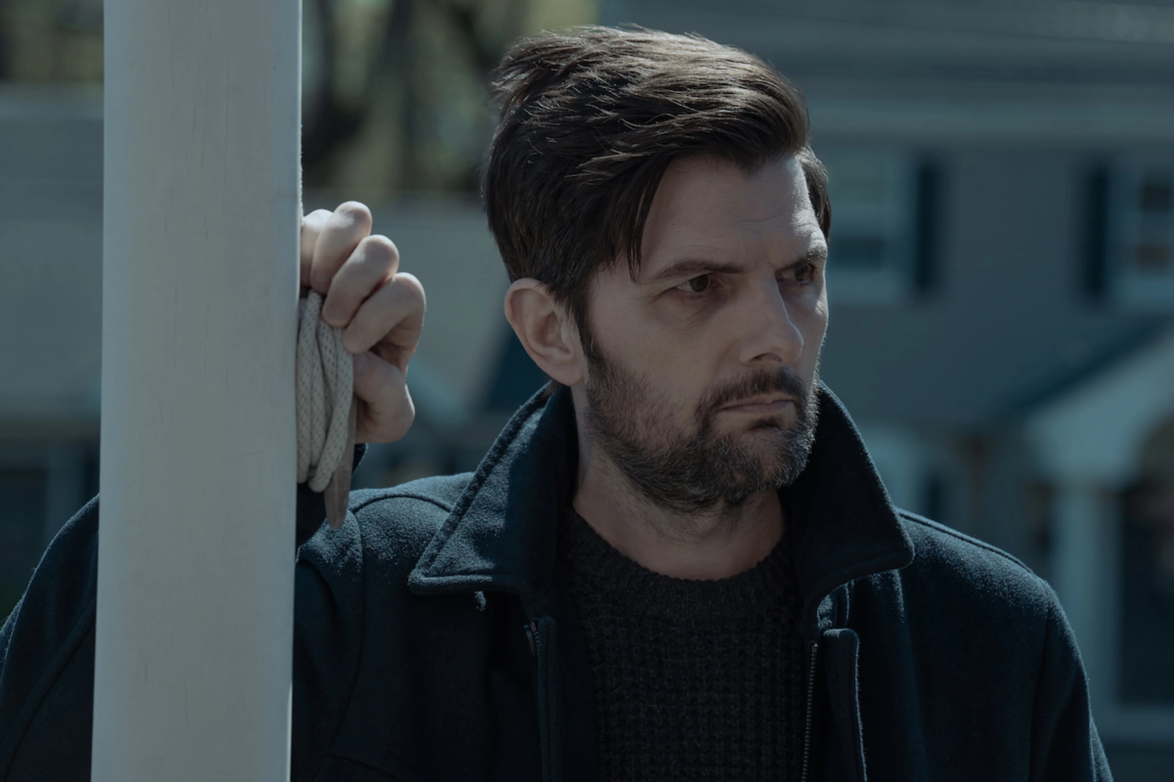 Adam Scott as Tom Kennedy searches outside a house in The Whisper Man.
