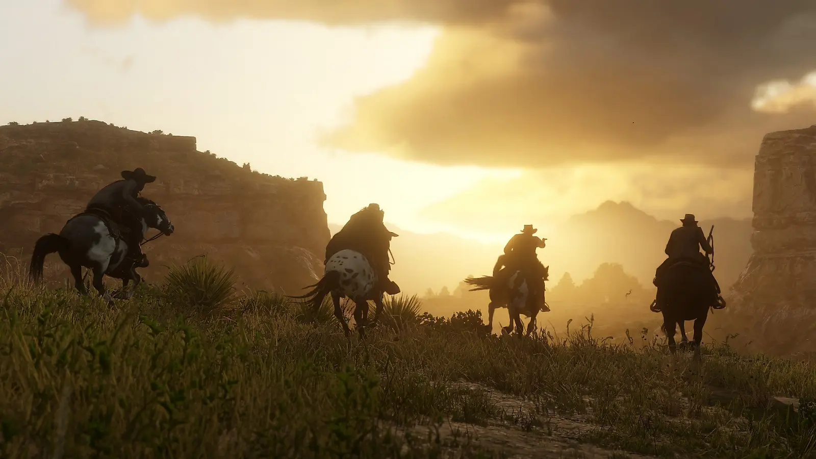 Four riders traveling through a canyon at sunset in Red Dead Redemption 2.