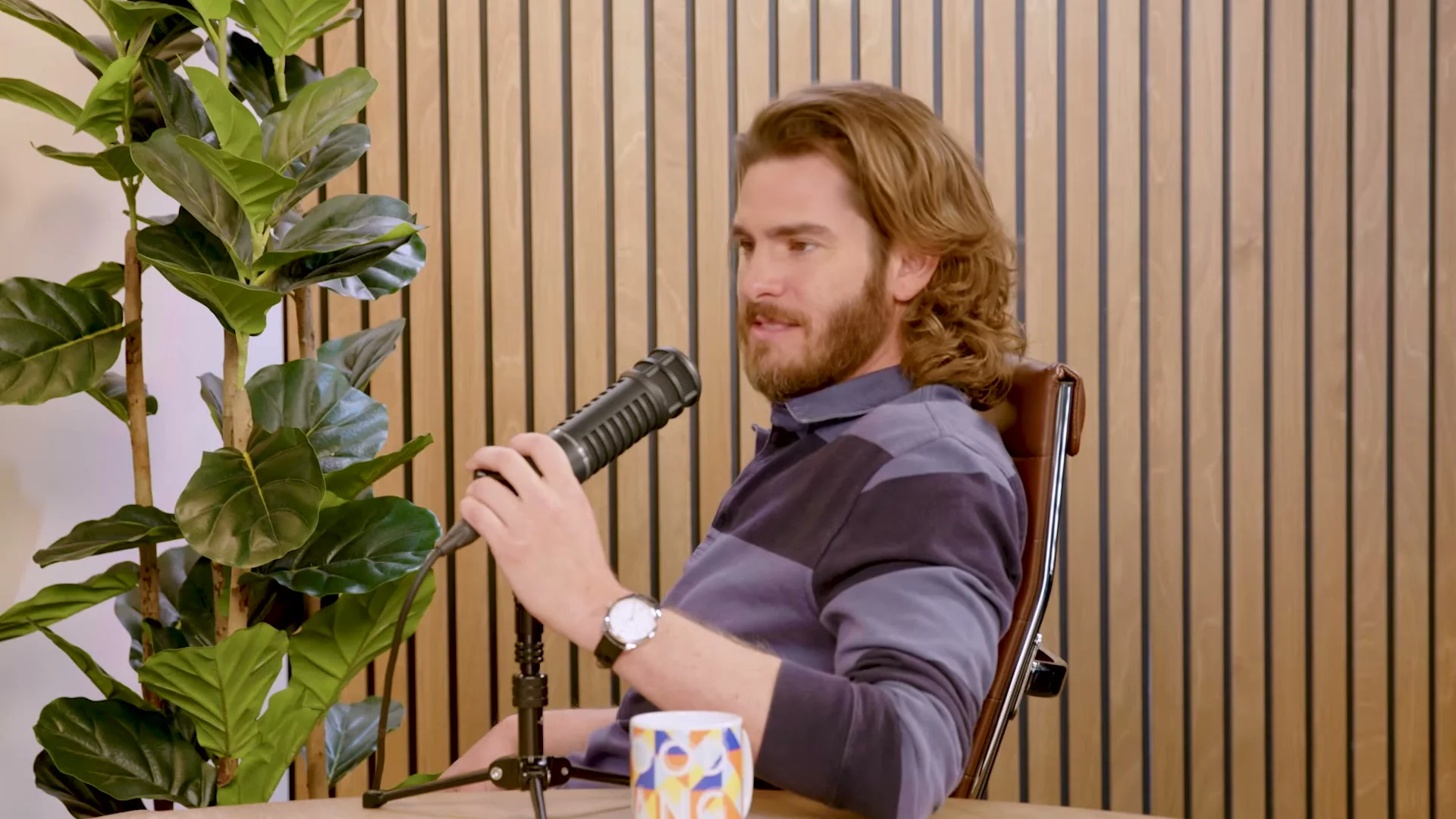 Andrew Garfield listens beside a microphone on the Good Hang set.