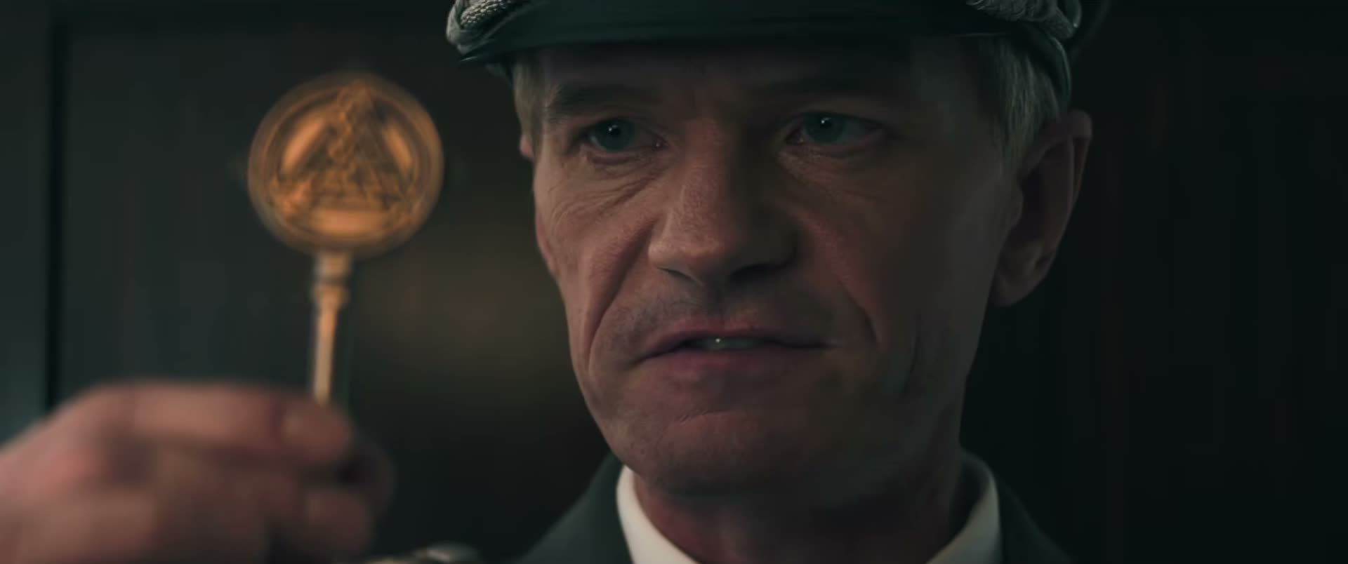 Neil Patrick Harris wears a military cap as Wilhelm Reuss, holding a key in The Last Temptation of Becky.