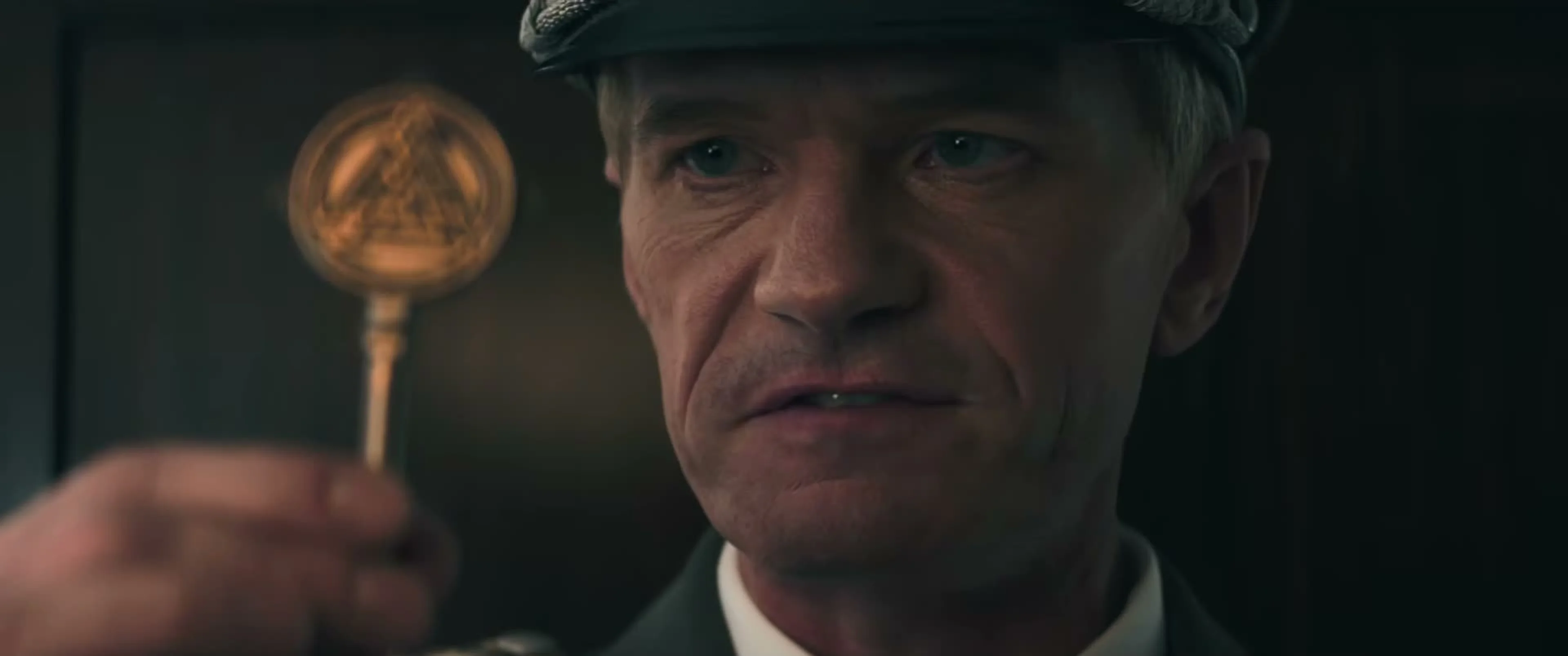 Neil Patrick Harris wears a military cap as Wilhelm Reuss, holding a key in The Last Temptation of Becky.