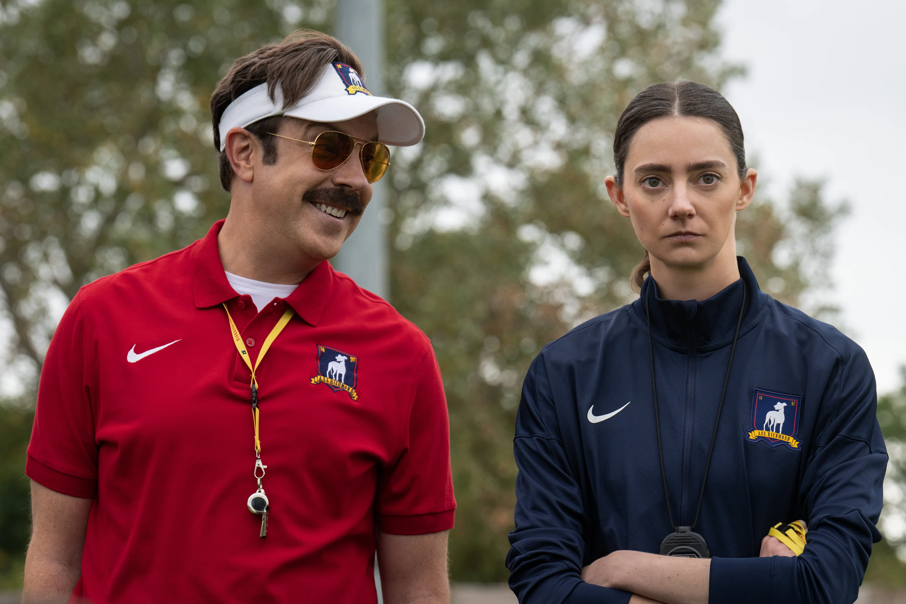 Jason Sudeikis and Tanya Reynolds stand beside a football field in Ted Lasso Season 4.