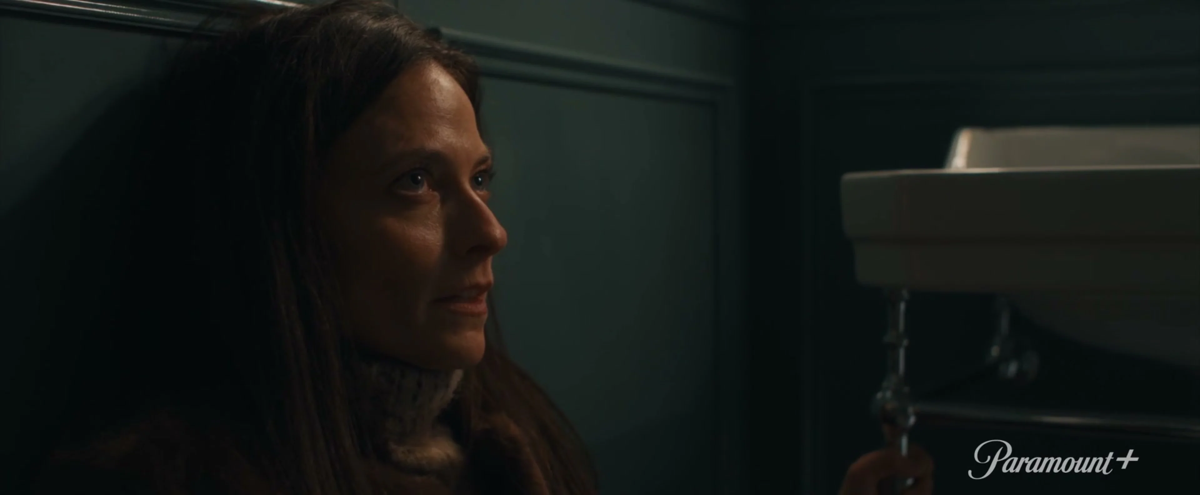 A woman looks across a dim room in the MobLand season-two trailer.