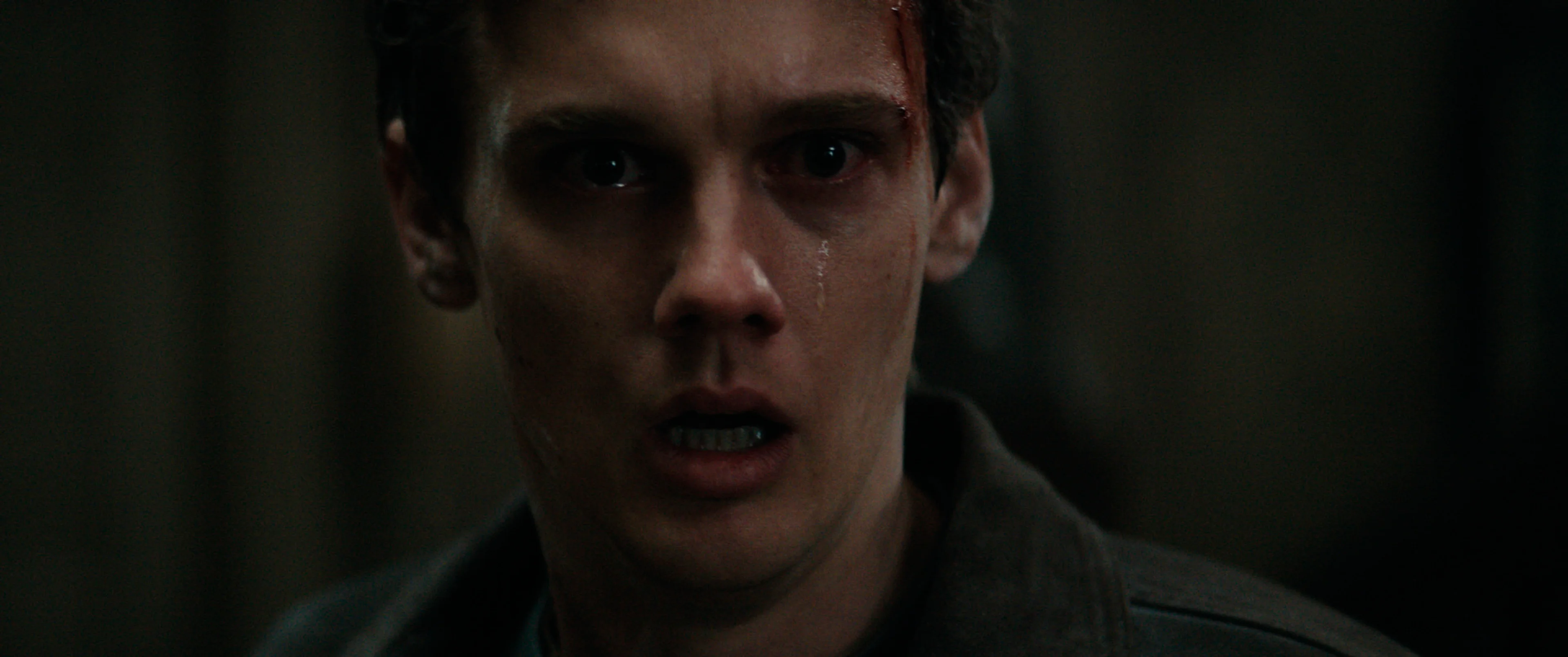 A man in Evil Dead Burn stands in dim light.