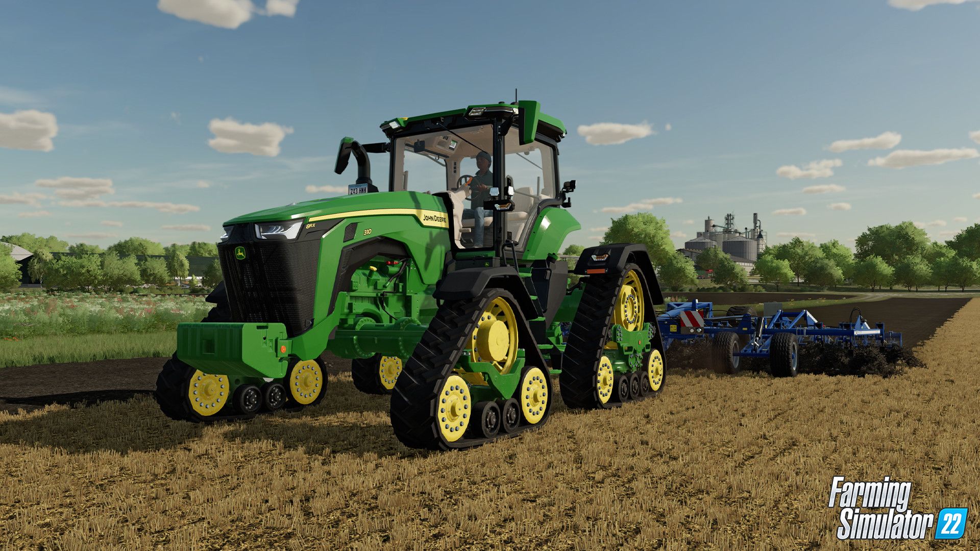 A large green tractor pulls equipment across a worked field.