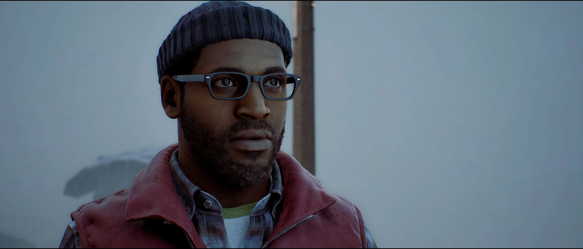 Simon Ordell wears glasses, a knitted hat and a red jacket in a foggy street.