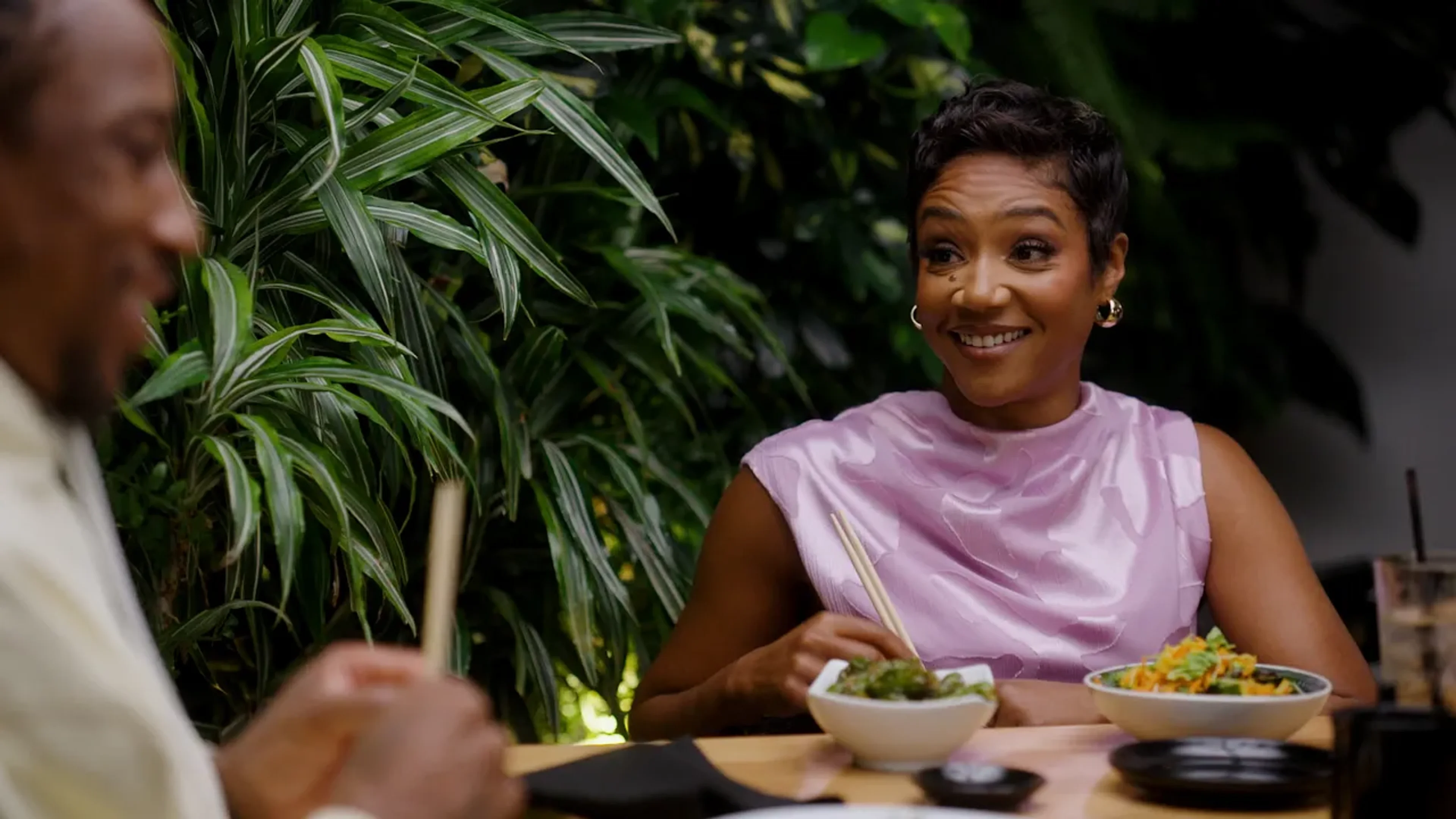 Tiffany Haddish talks with DeMar DeRozan across a dinner table.