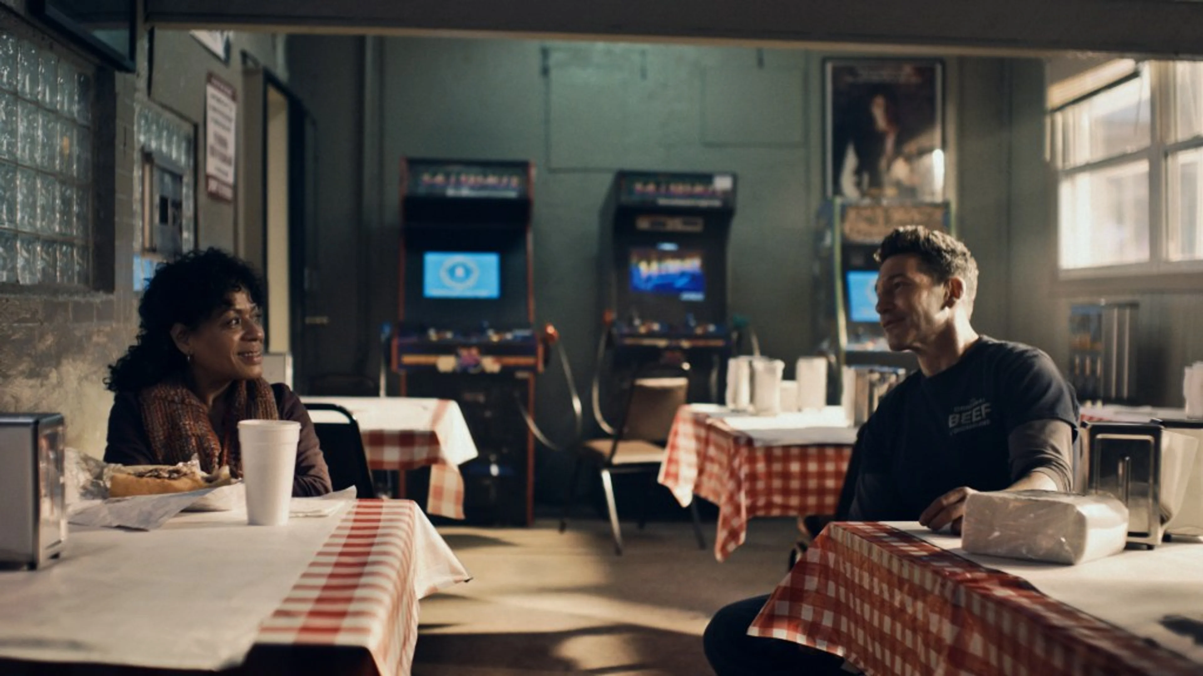Tina and Mikey sit at separate tables and talk inside the Original Beef in “Napkins”.