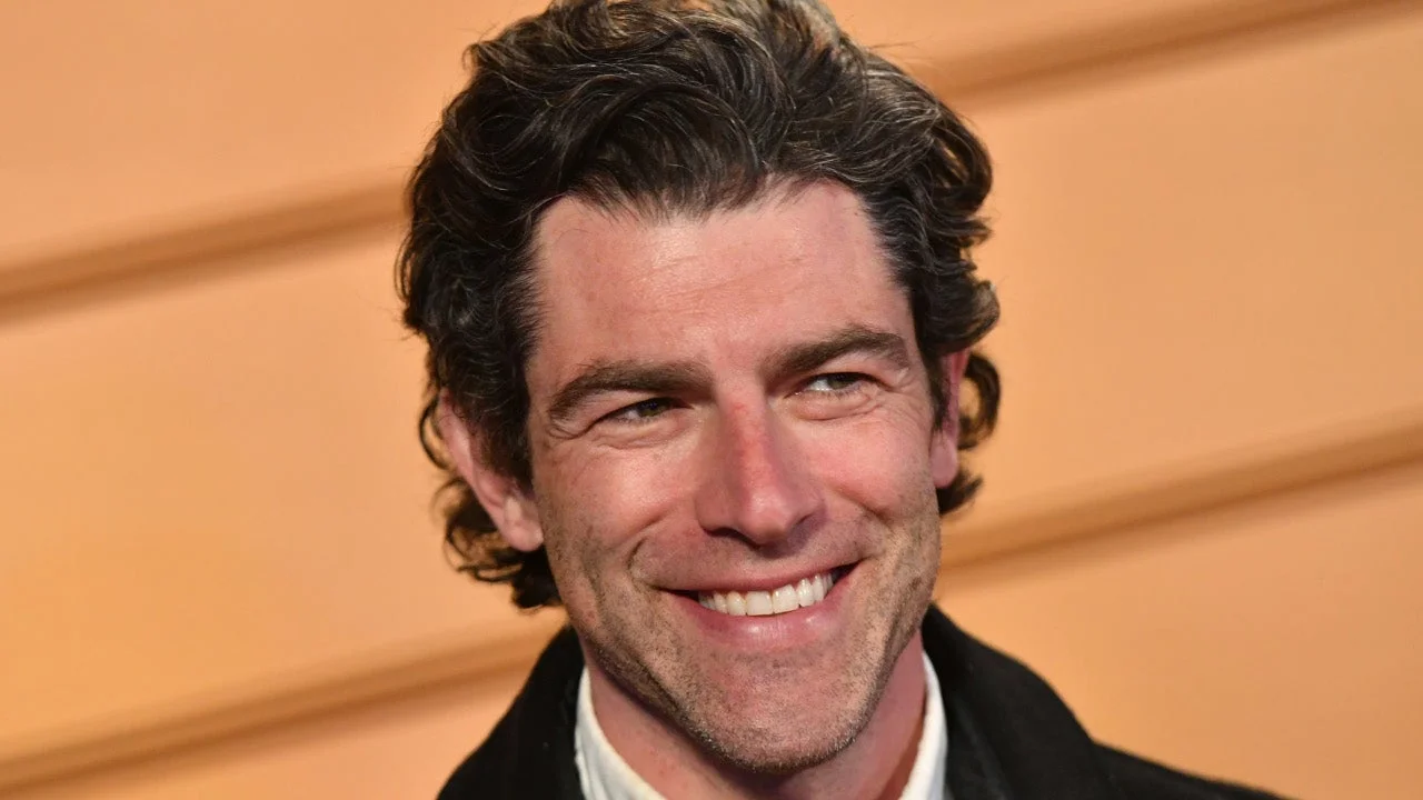 Max Greenfield smiles in a close-up portrait.