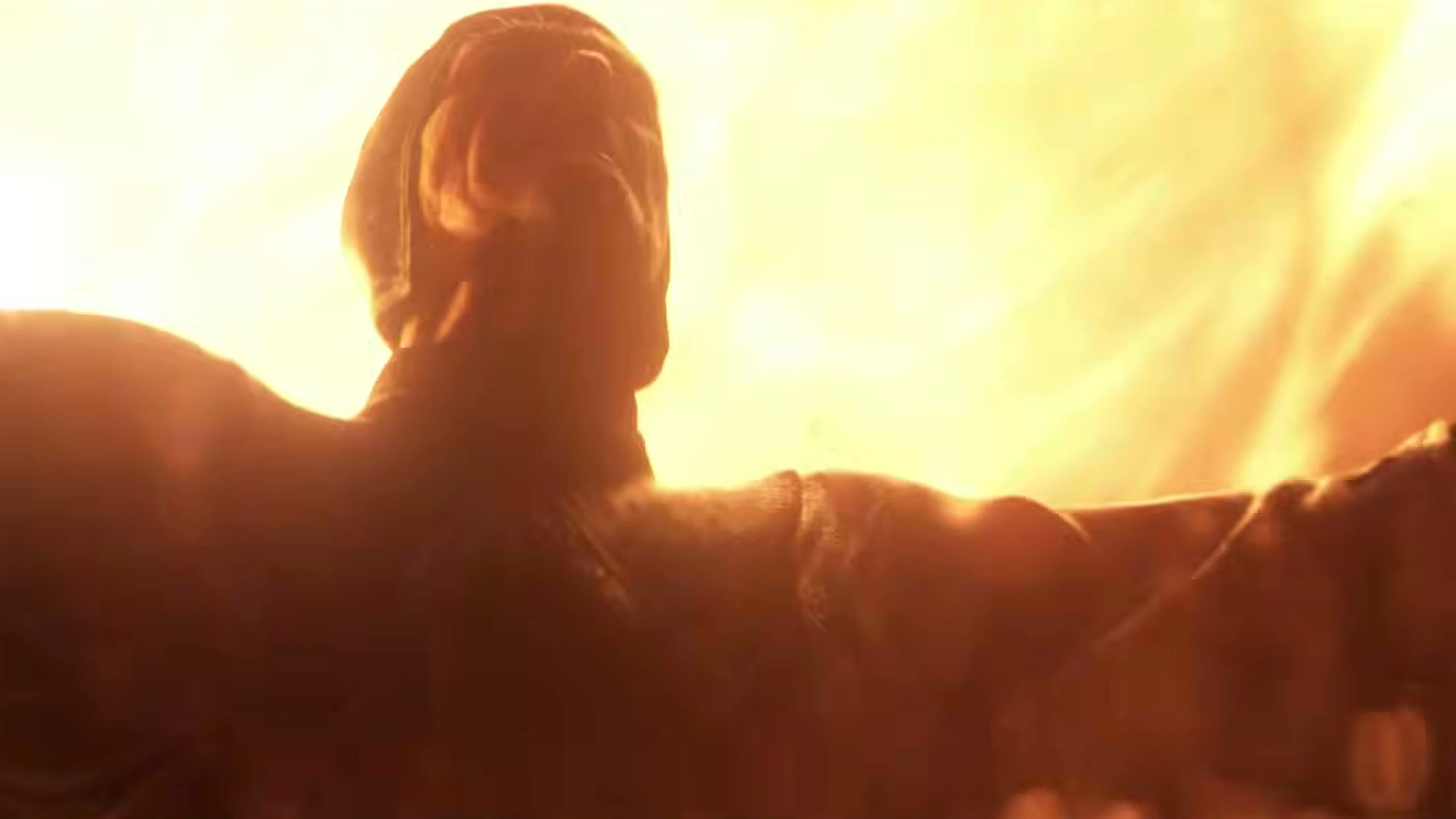 A human silhouette faces the camera while fire fills the background.