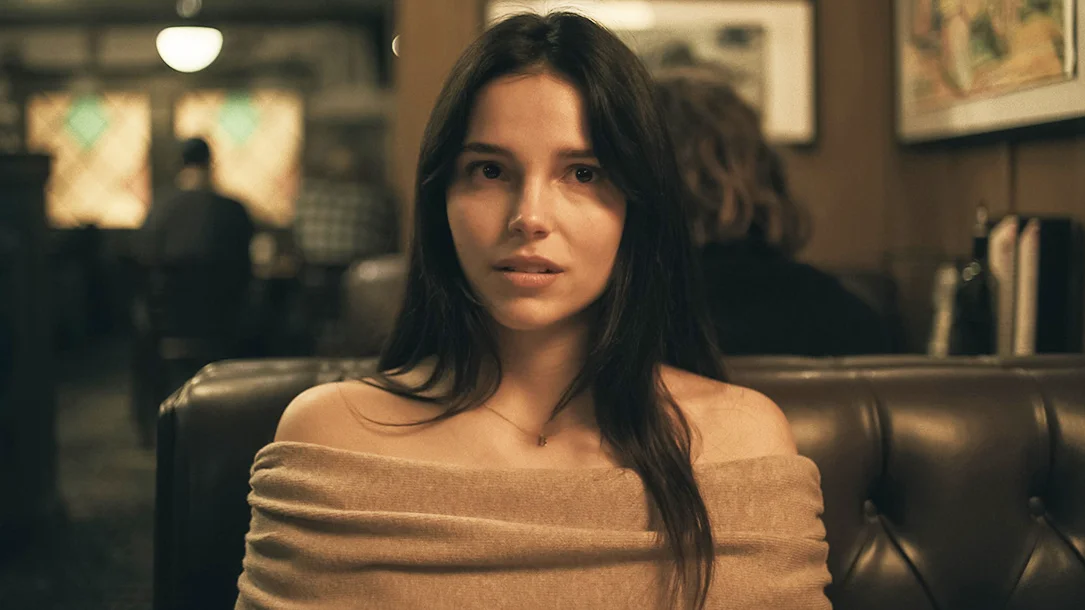 Inde Navarrette as Nikki, seated in a restaurant booth.