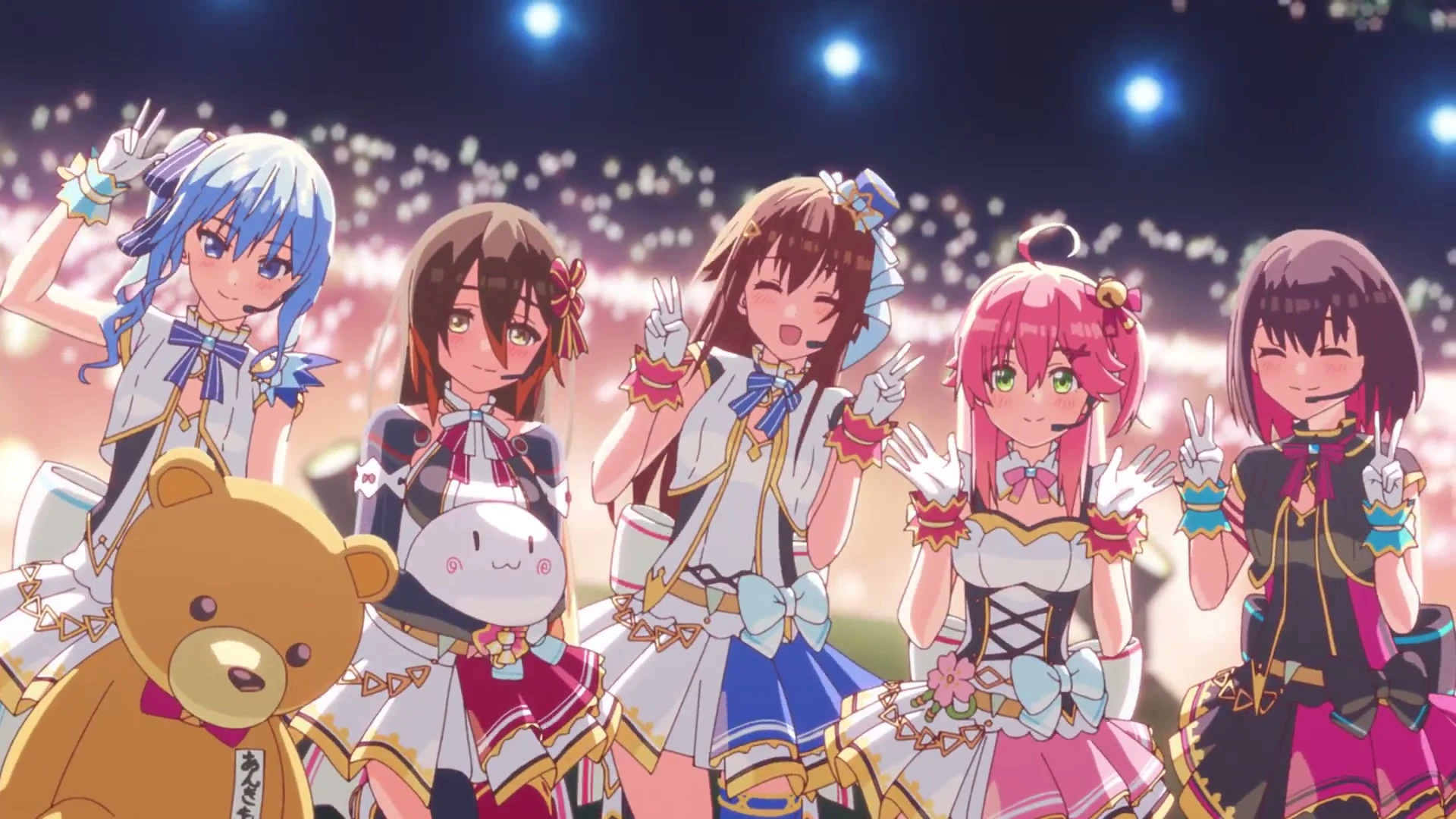 Five animated hololive performers pose together under bright lights on a concert stage.