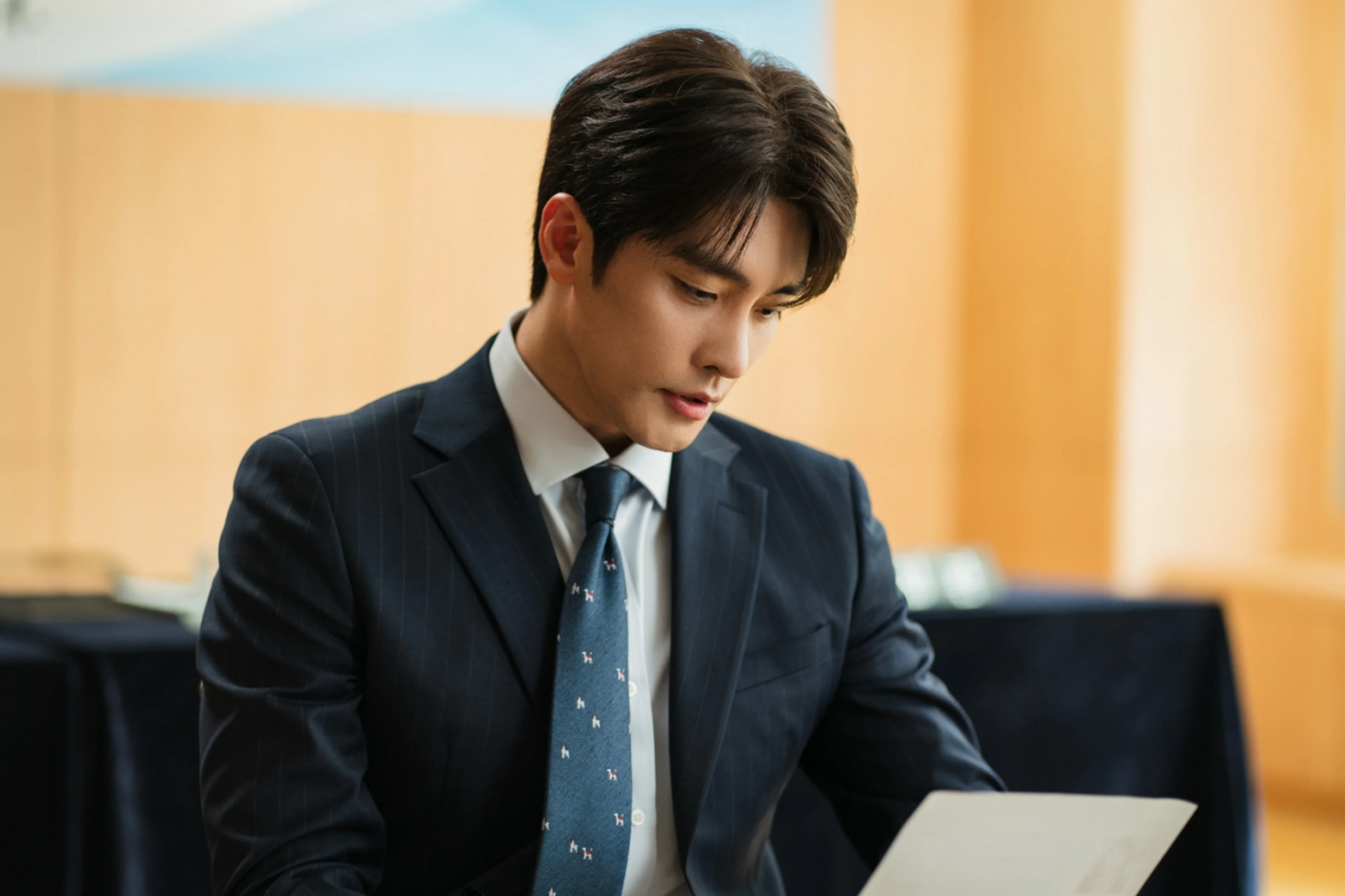 Sung Hoon as Kwon Do-hyuk reads a document in a navy suit in What a Boss Wants.