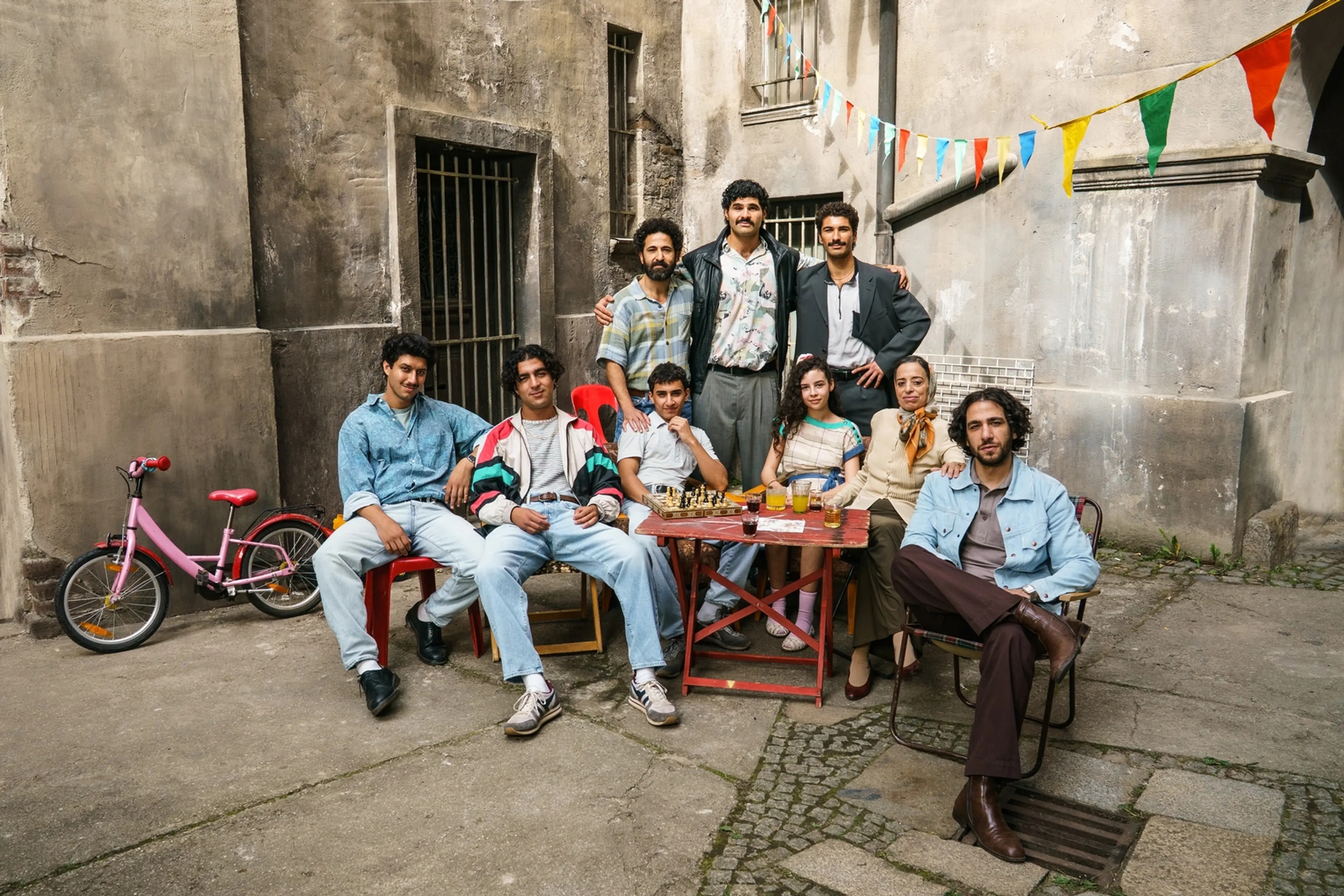 The Hamady family gathers around an outdoor table in a 1990s Berlin courtyard in 4 Blocks Zero.