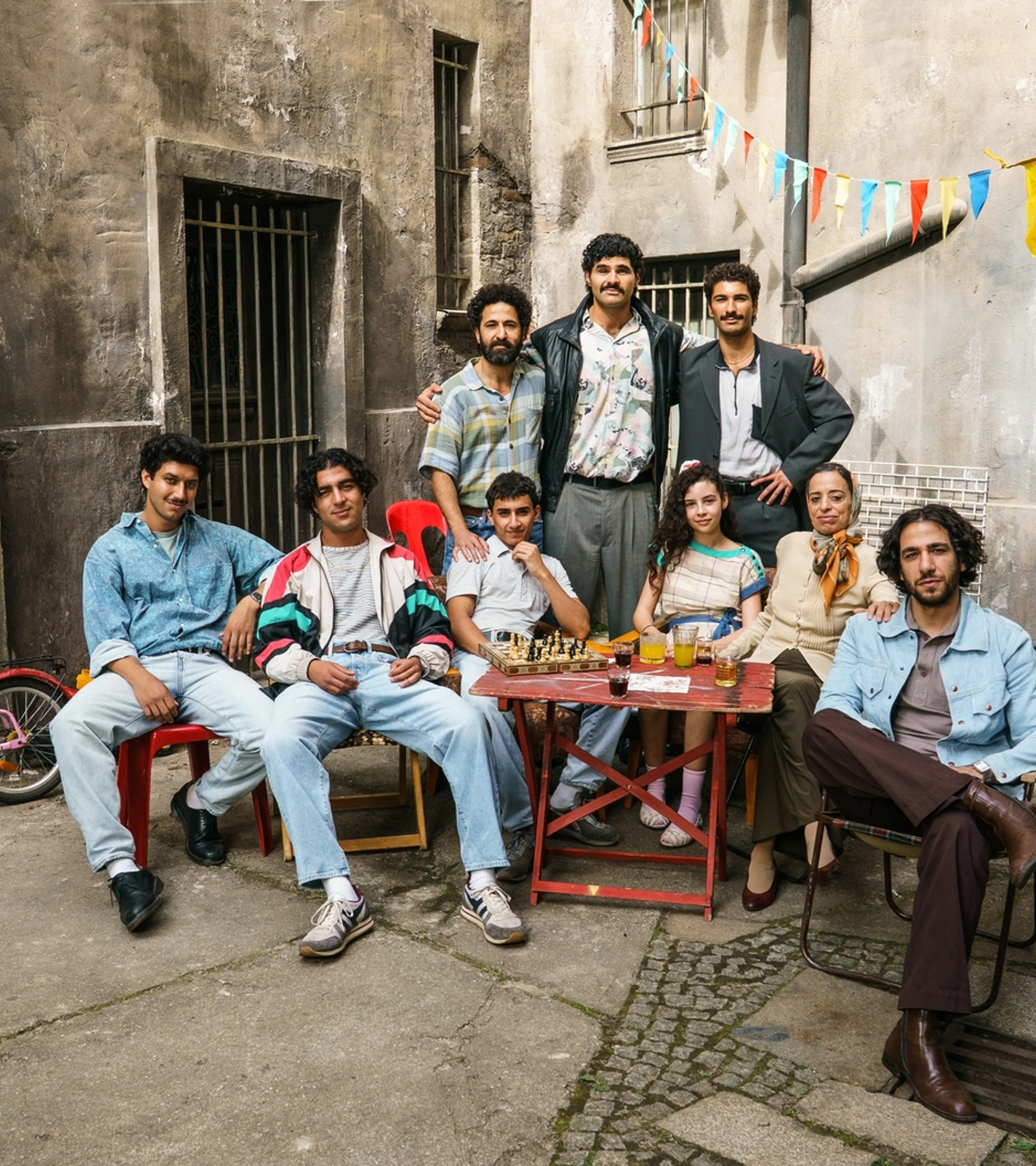 The Hamady family gathers around an outdoor table in a 1990s Berlin courtyard in 4 Blocks Zero.