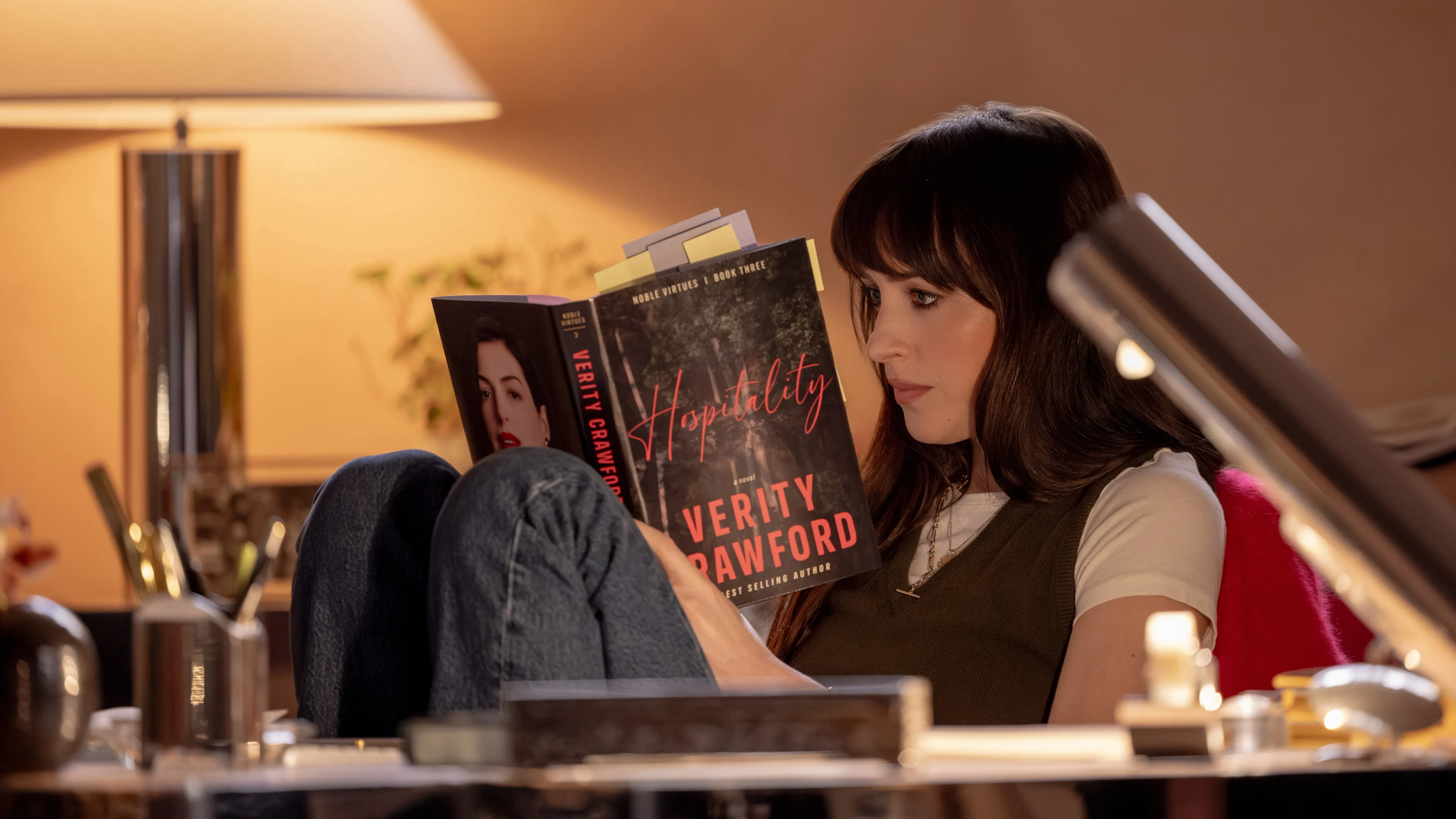 Dakota Johnson as Lowen reads a Verity Crawford book inside the Crawford home.