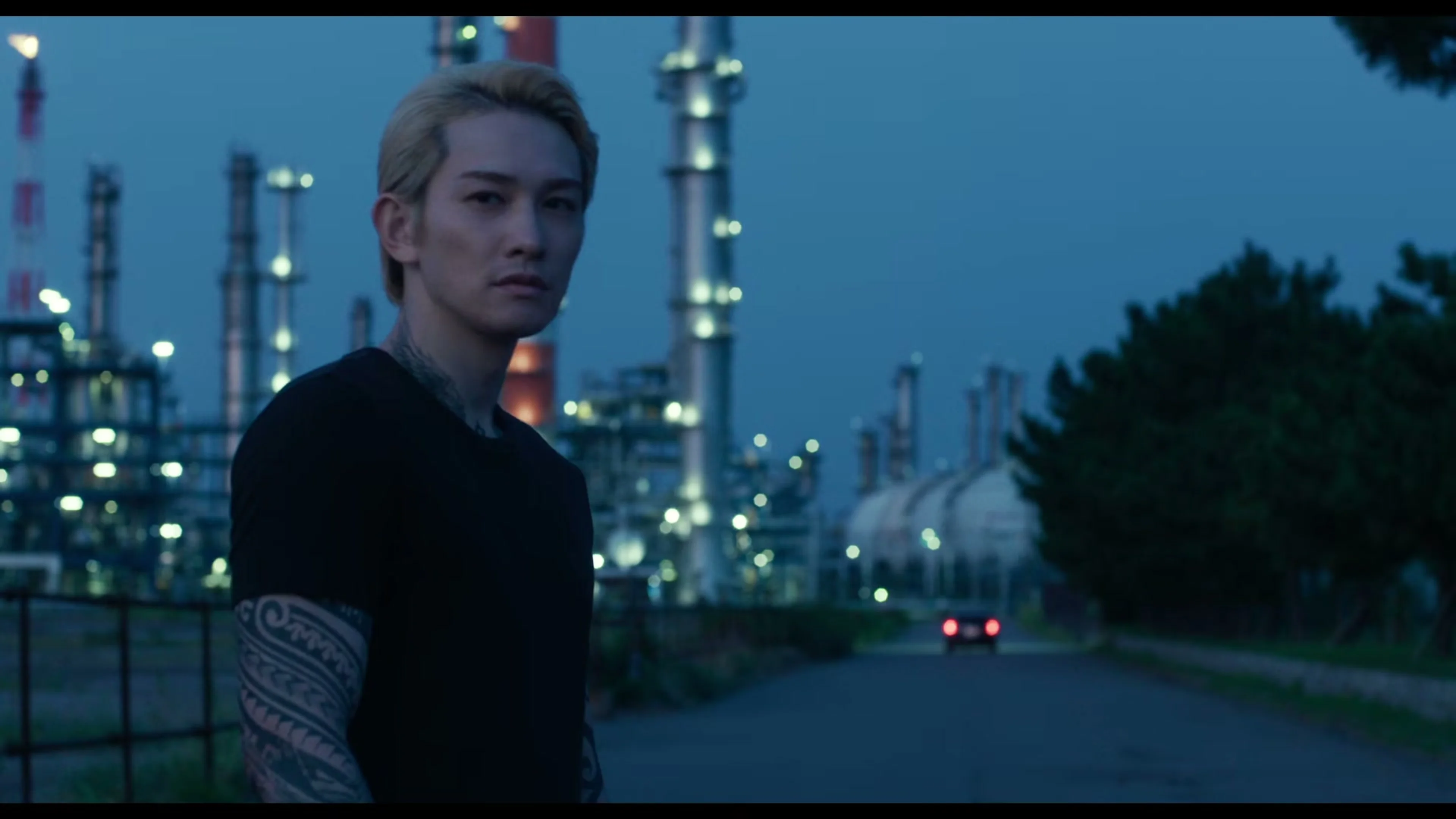 A tattooed man stands near an industrial waterfront in the new Sins of Kujo movie teaser.