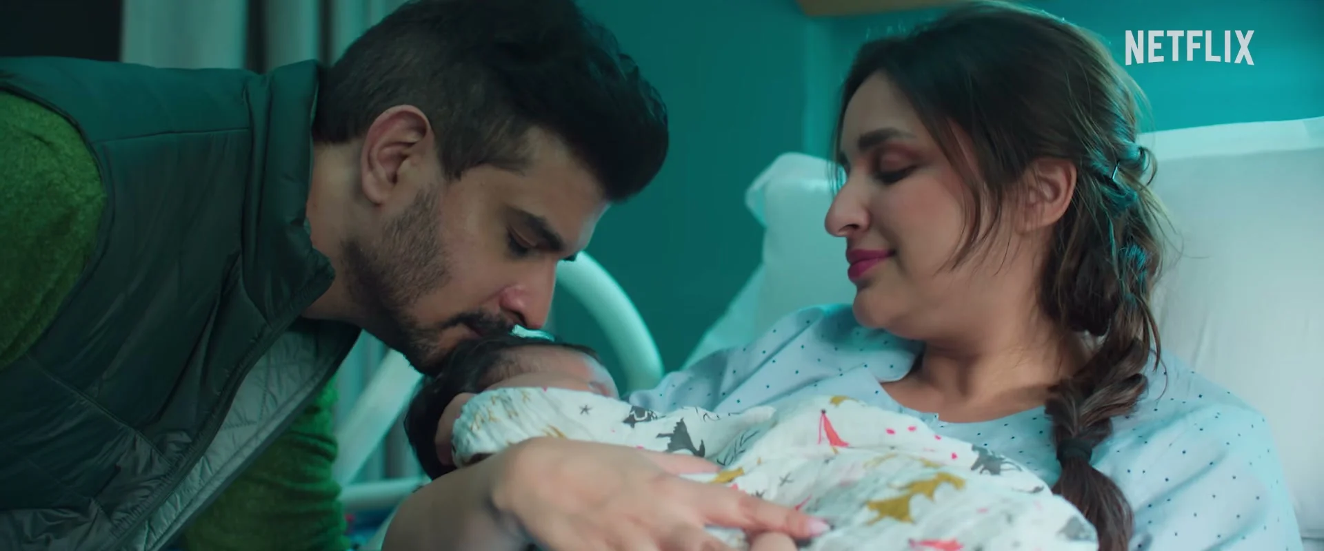 Tahir Raj Bhasin as Alok kisses his newborn daughter while Parineeti Chopra as Anvita holds her in a hospital bed.