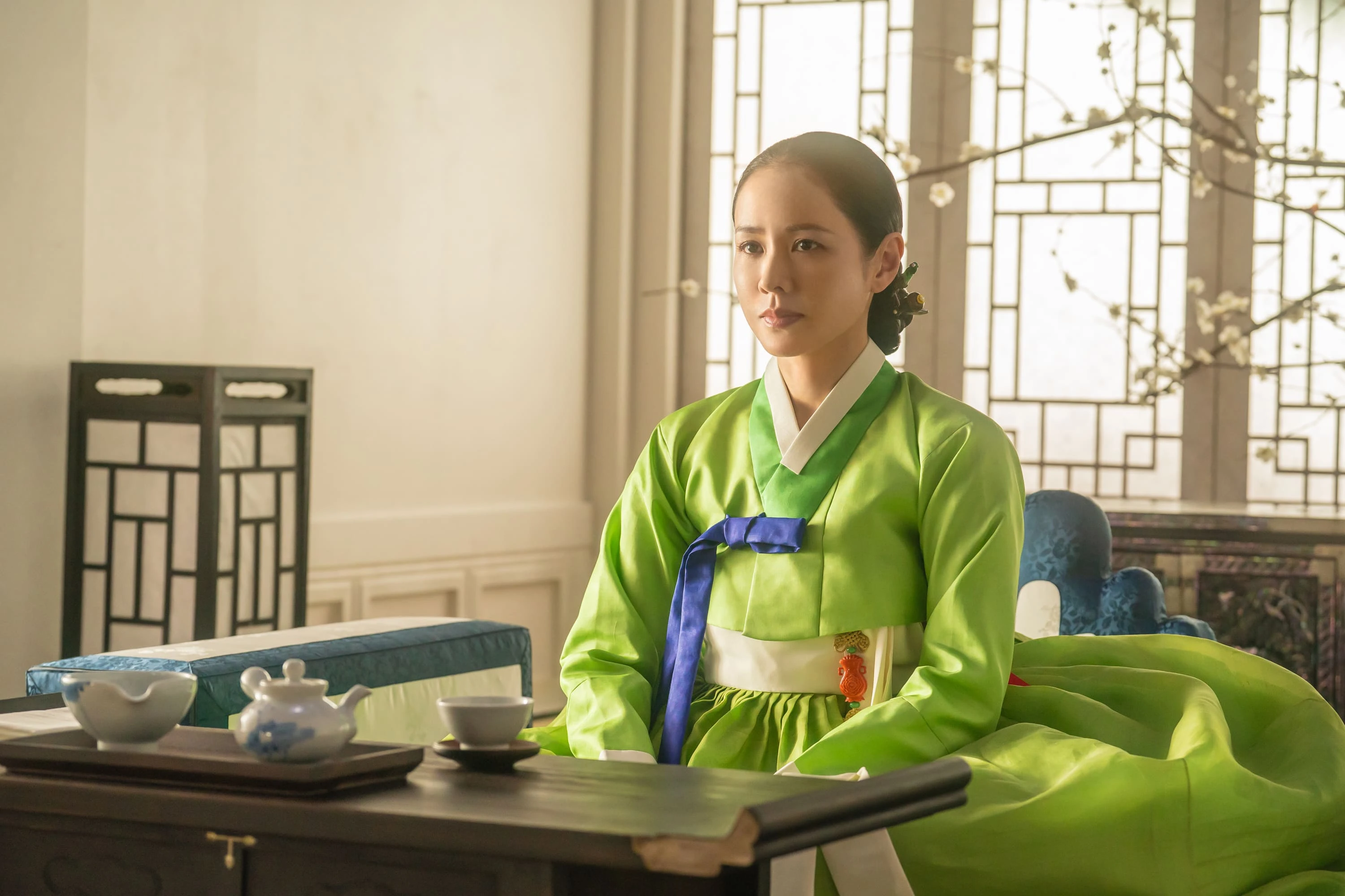 Son Ye-jin sits beside a low table wearing a bright green hanbok.