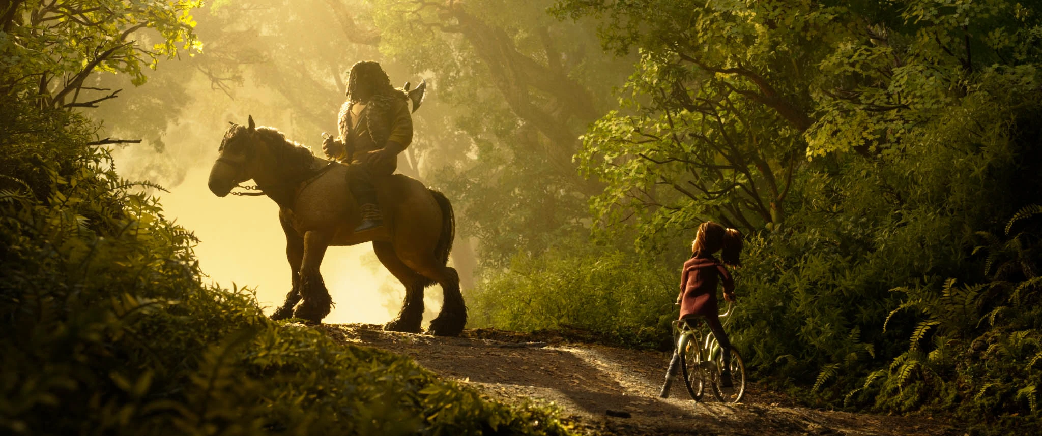 Prue rides a bicycle toward a horseman on a sunlit forest path in Wildwood.