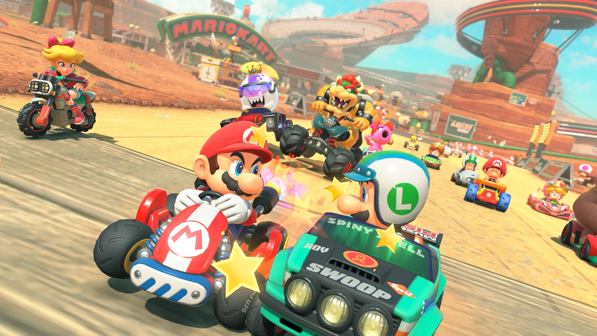 Mario races near Luigi, Peach and Bowser on a sunlit Mario Kart World road.