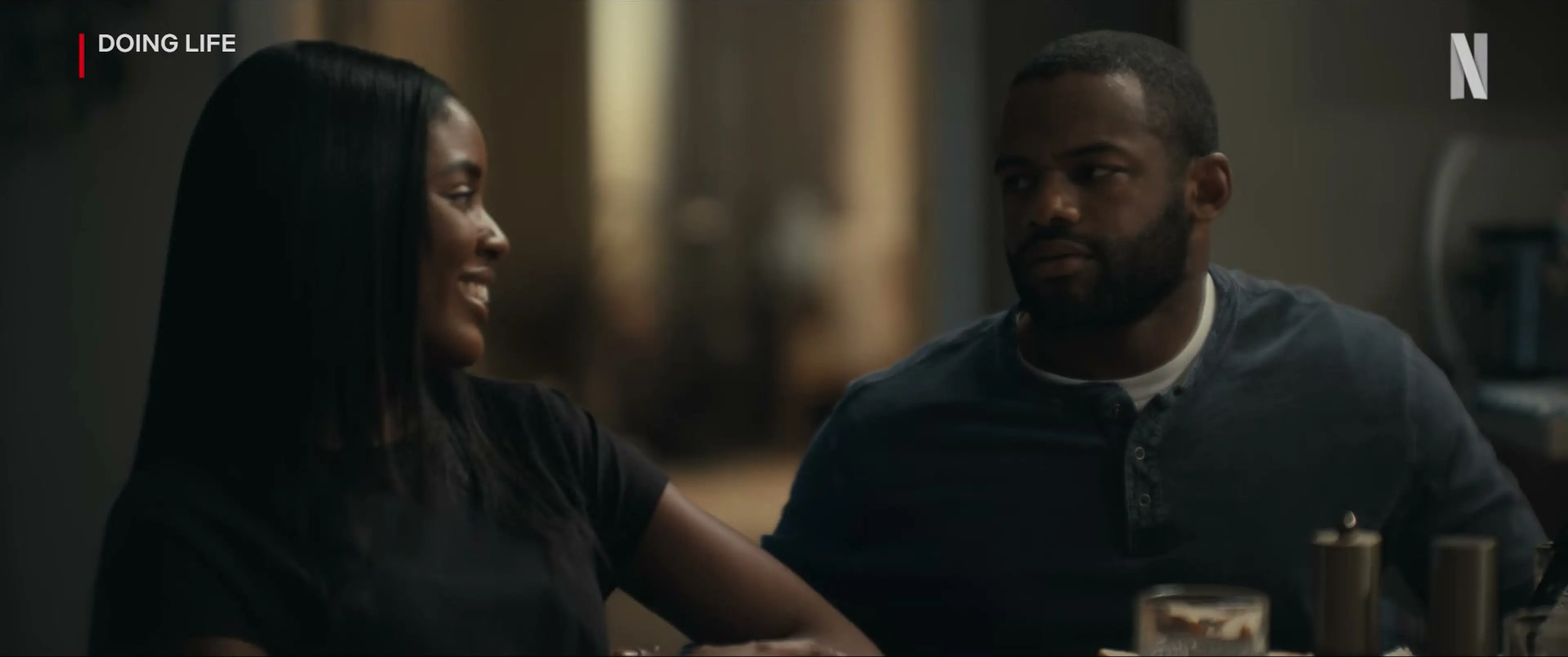 A woman and man face each other across a dinner table in Doing Life.