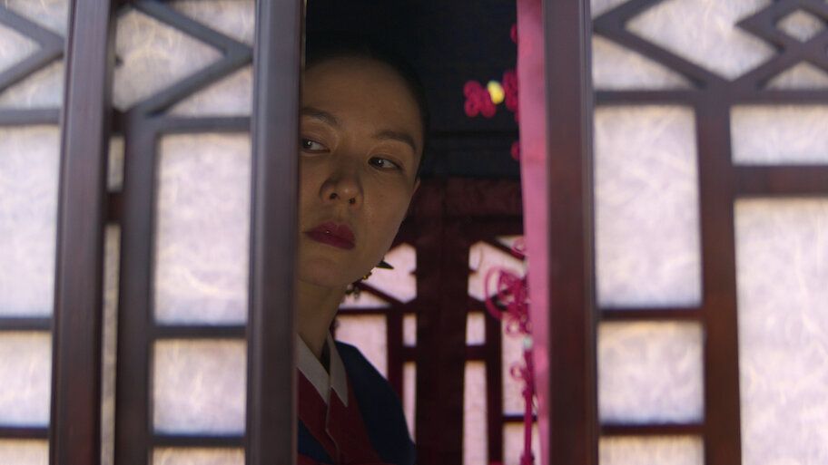 A woman peers through a doorway in a scene from The Scandal.