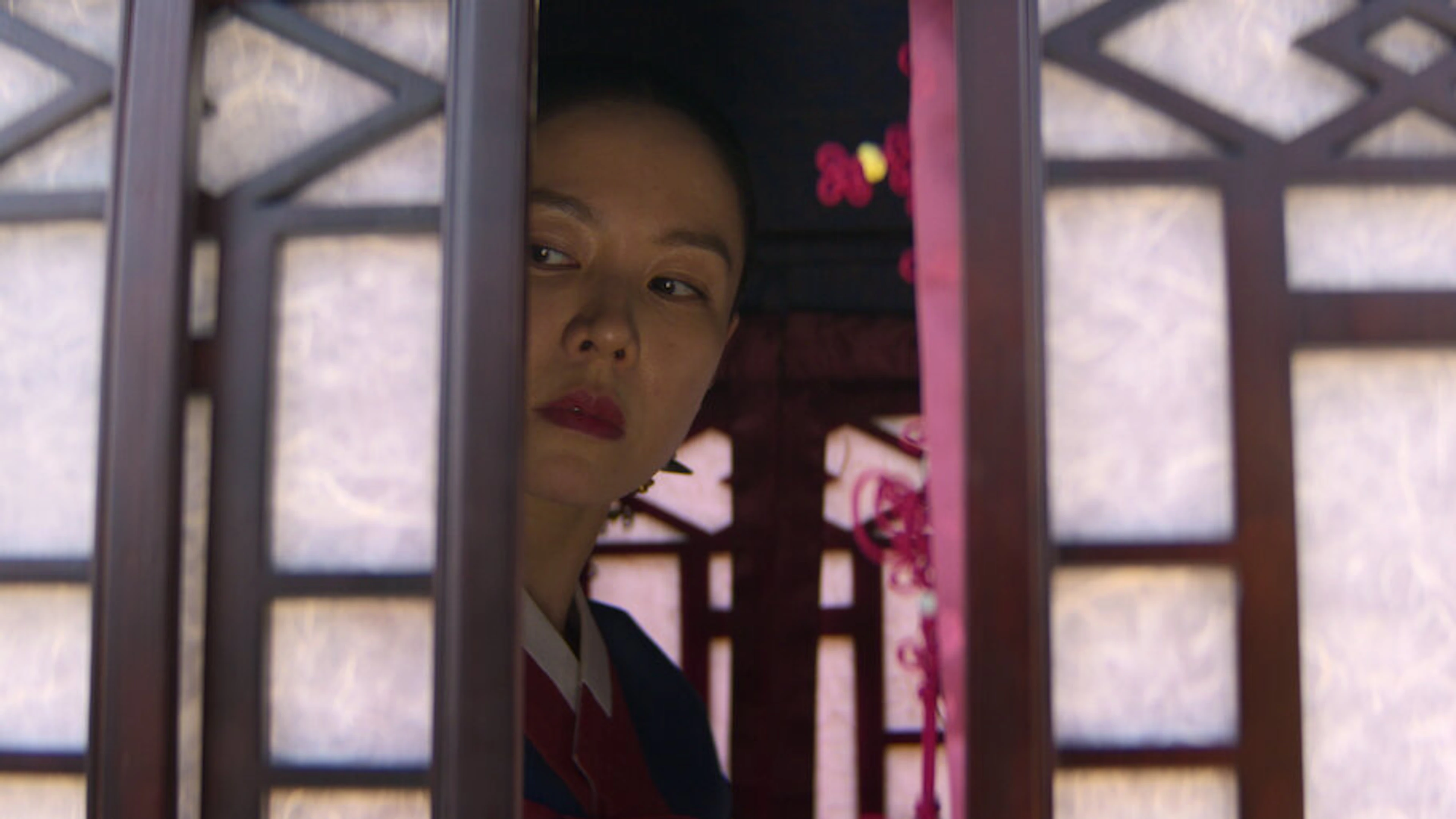 A woman peers through a doorway in a scene from The Scandal.
