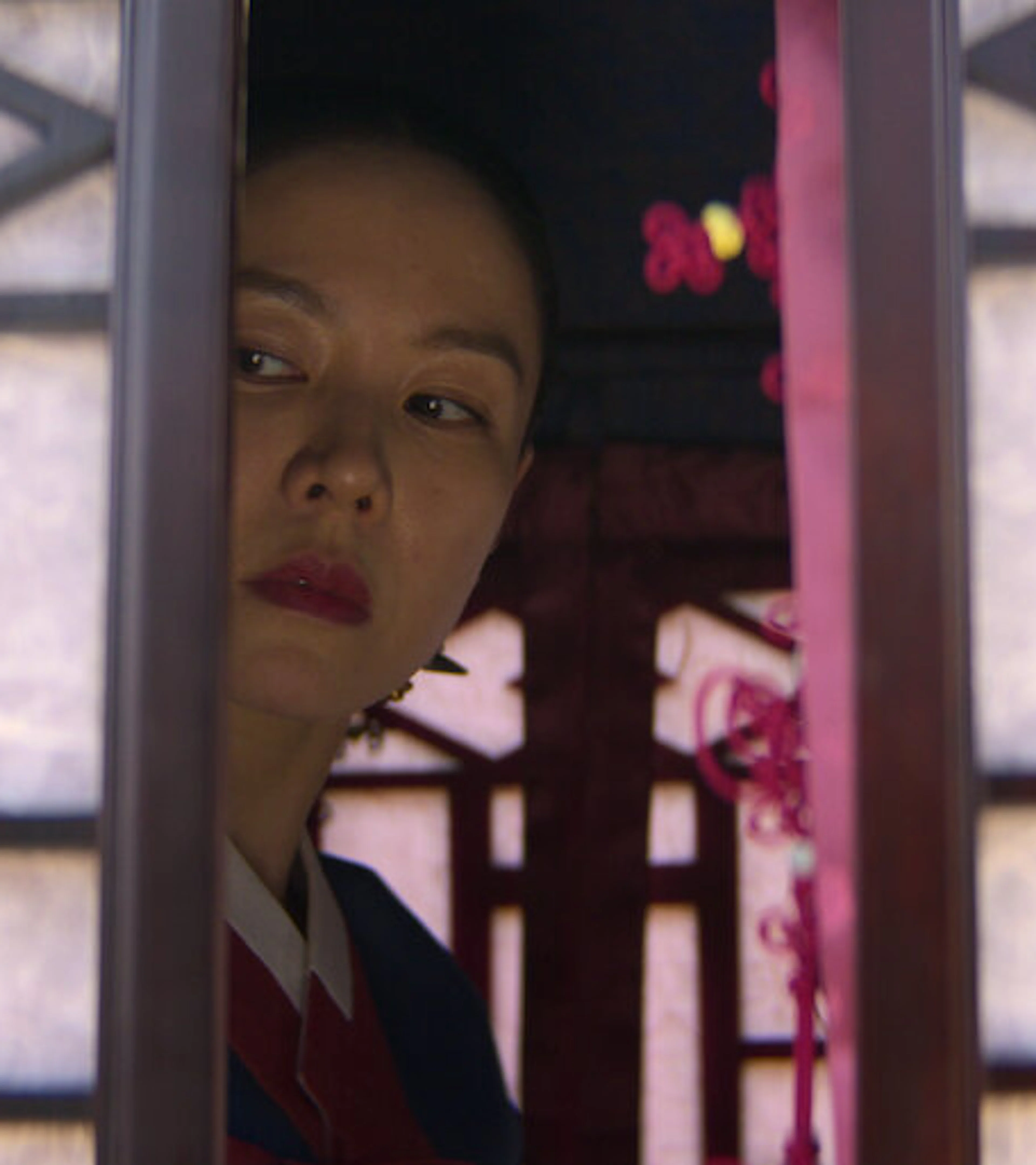 A woman peers through a doorway in a scene from The Scandal.