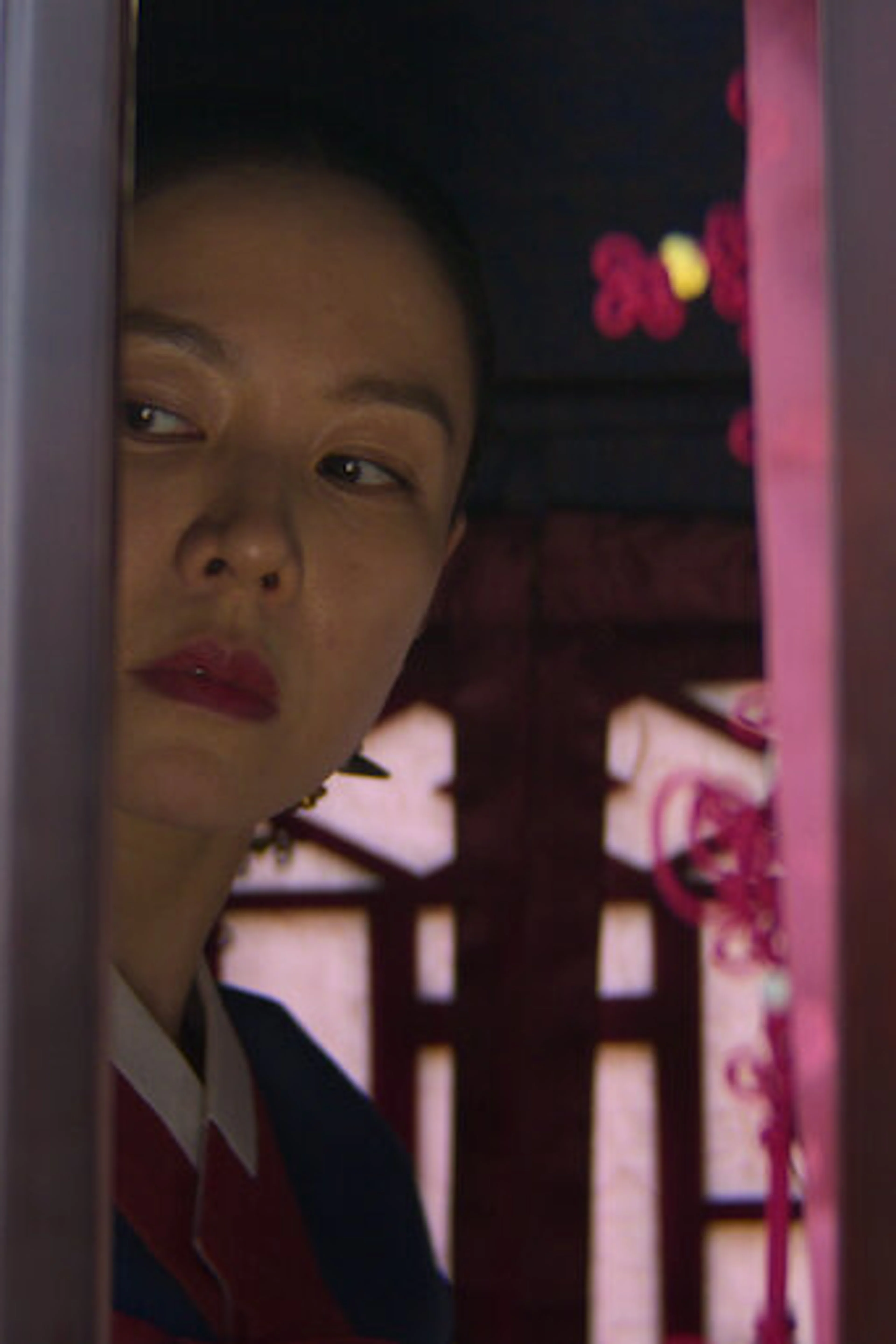 A woman peers through a doorway in a scene from The Scandal.