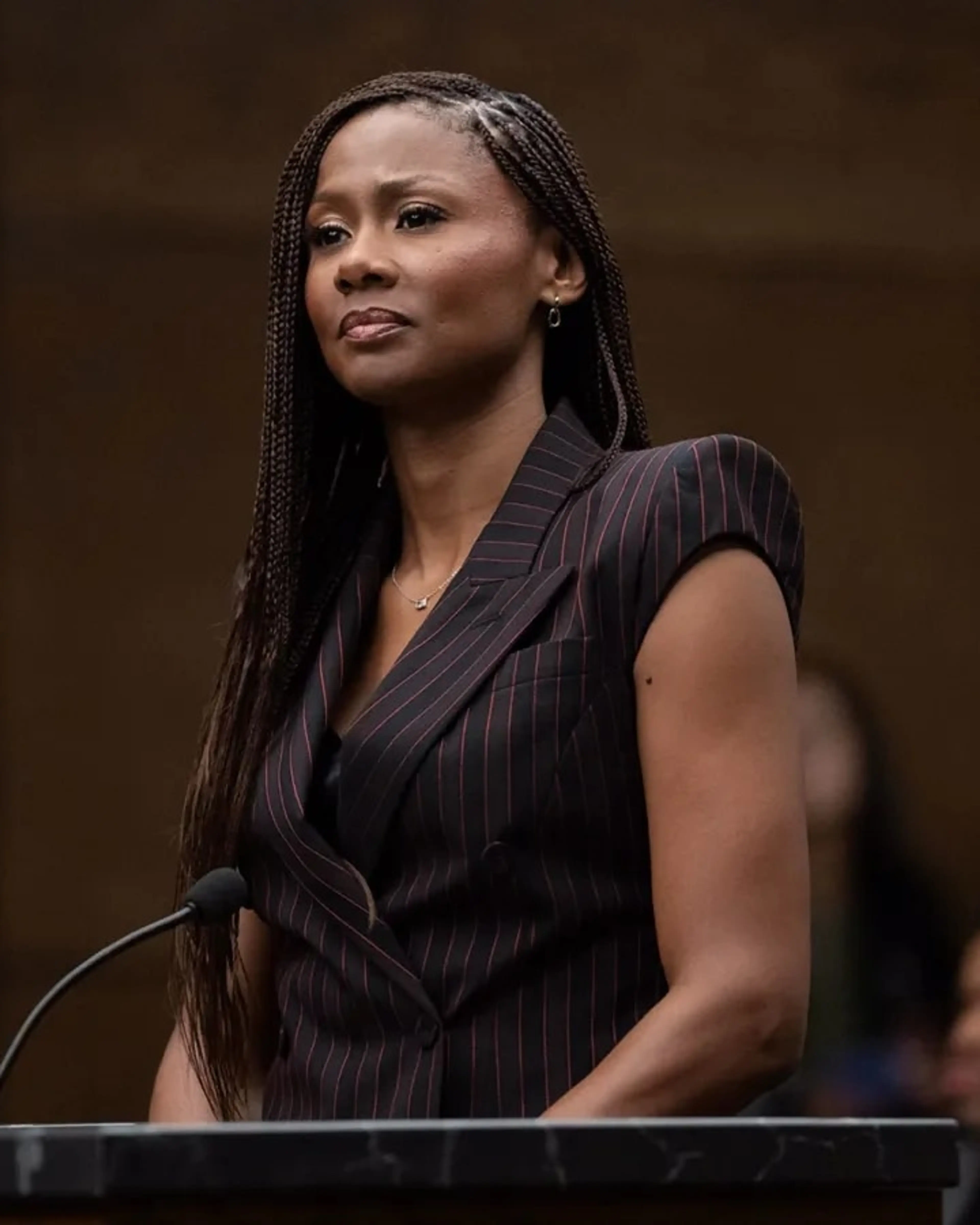 Emayatzy Corinealdi as Jax Stewart stands at a courtroom lectern.