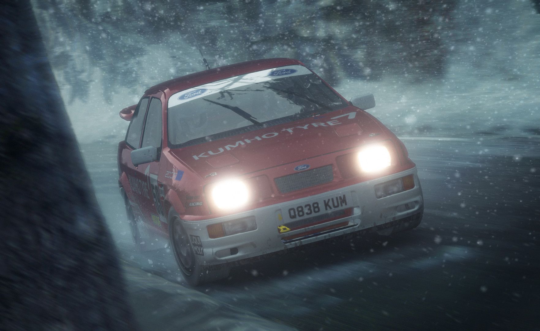 Red rally car approaches on a snowy road in low visibility.