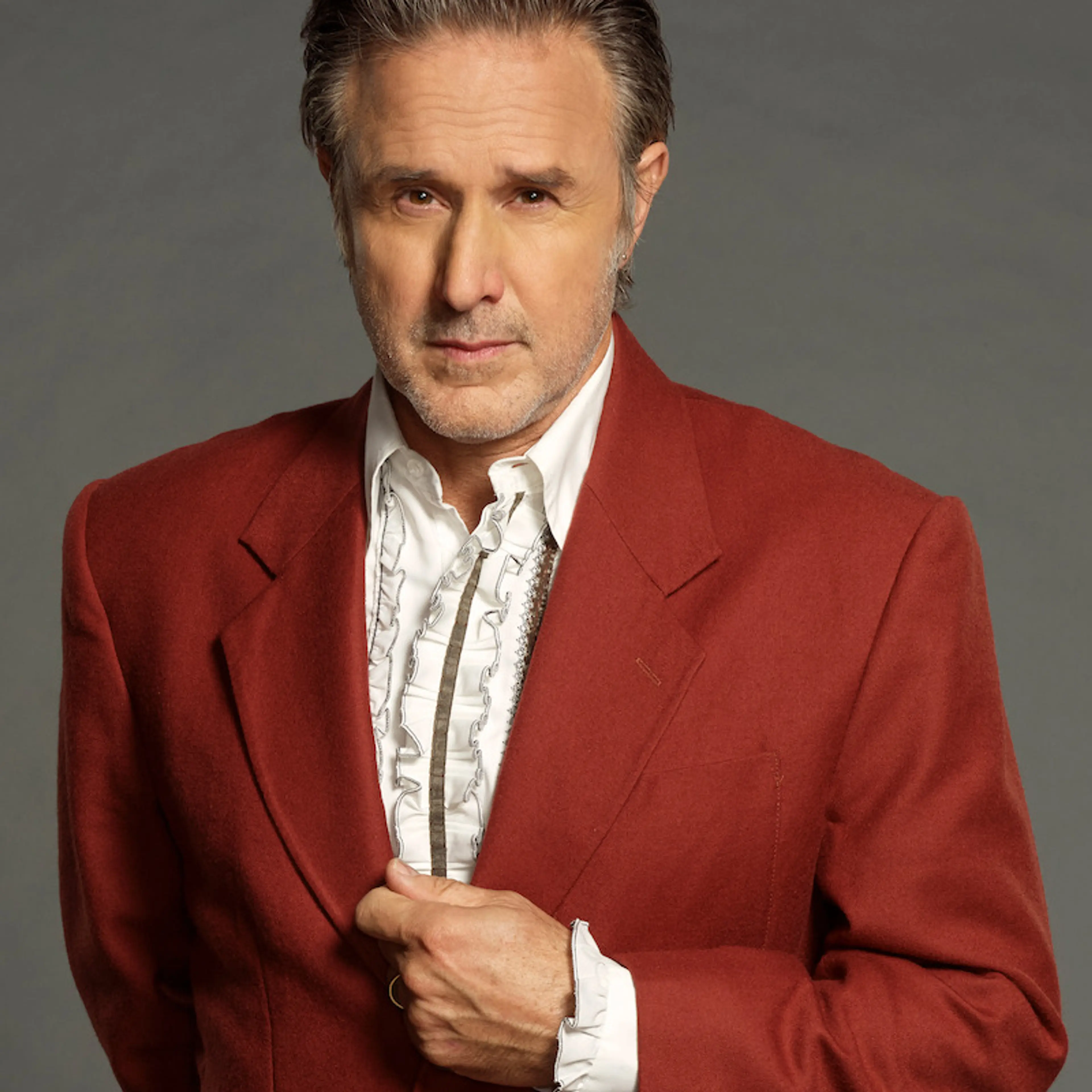 David Arquette poses in a red jacket for Celebrity Million Dollar Secret.